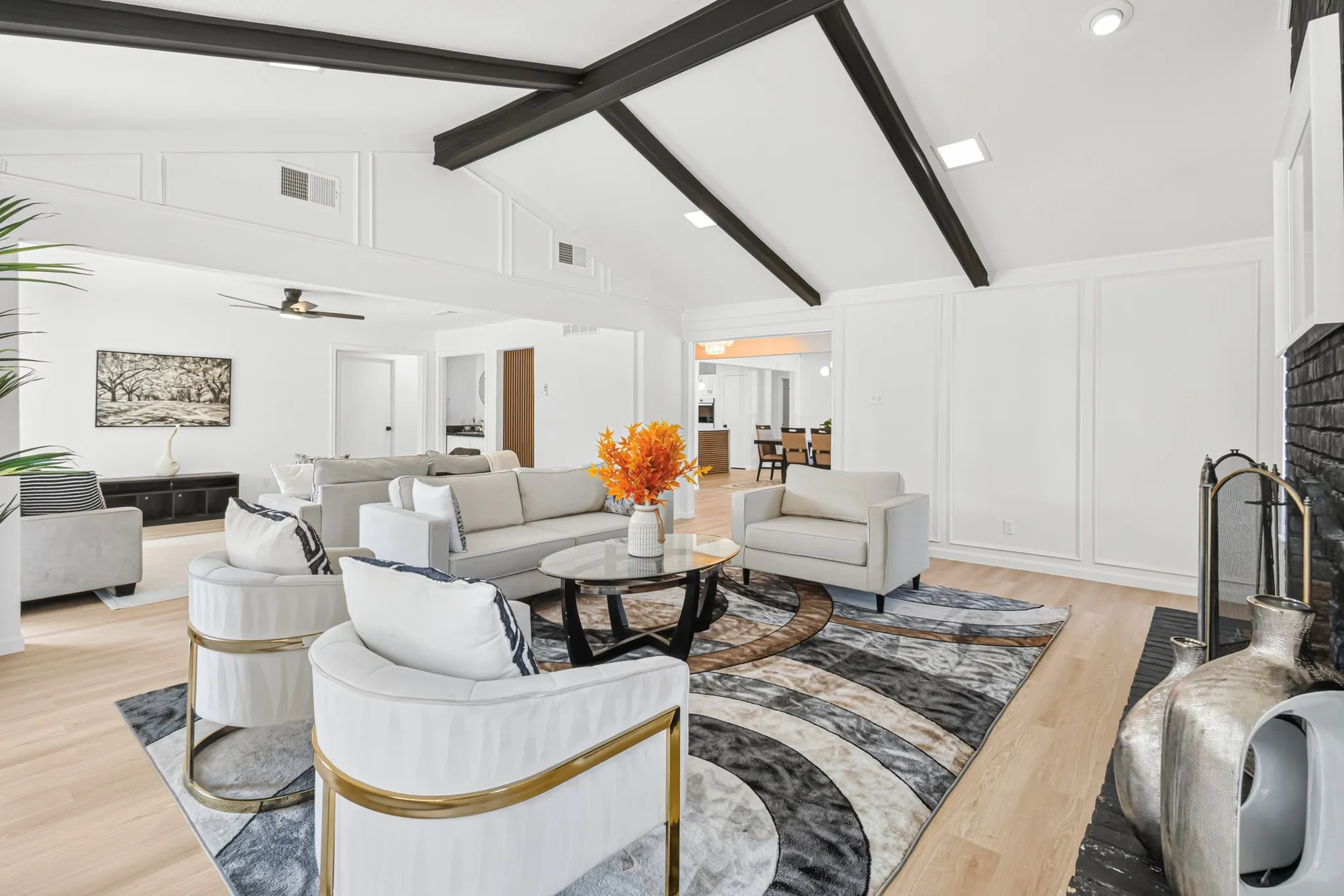 Vaulted ceiling with exposed beams, wood-finish flooring, white paneling, recessed lighting, and a black brick fireplace