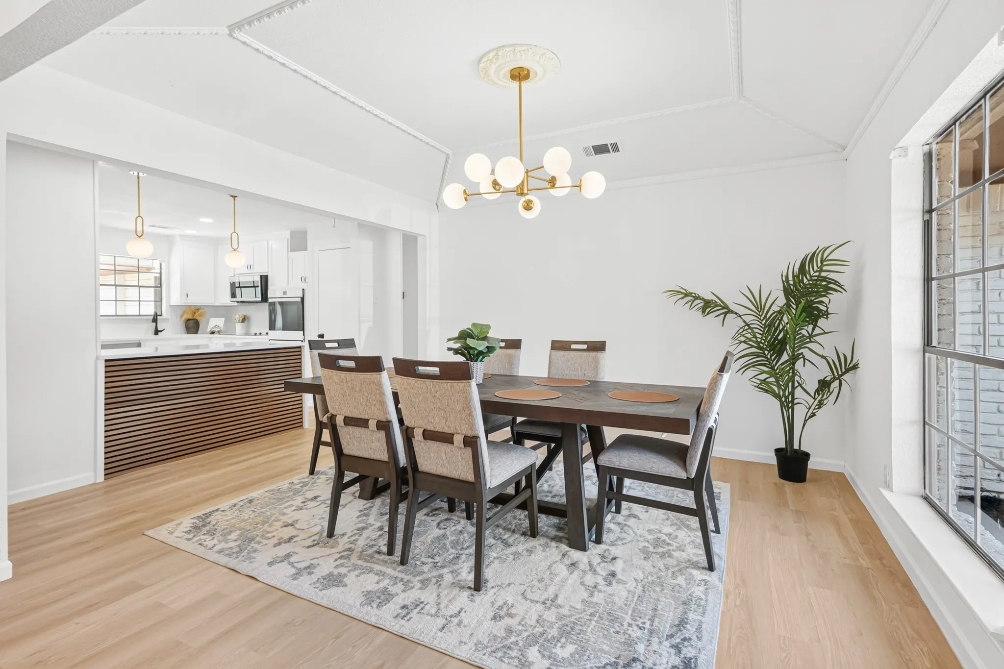 Light wood-finish flooring, white walls, and a modern chandelier