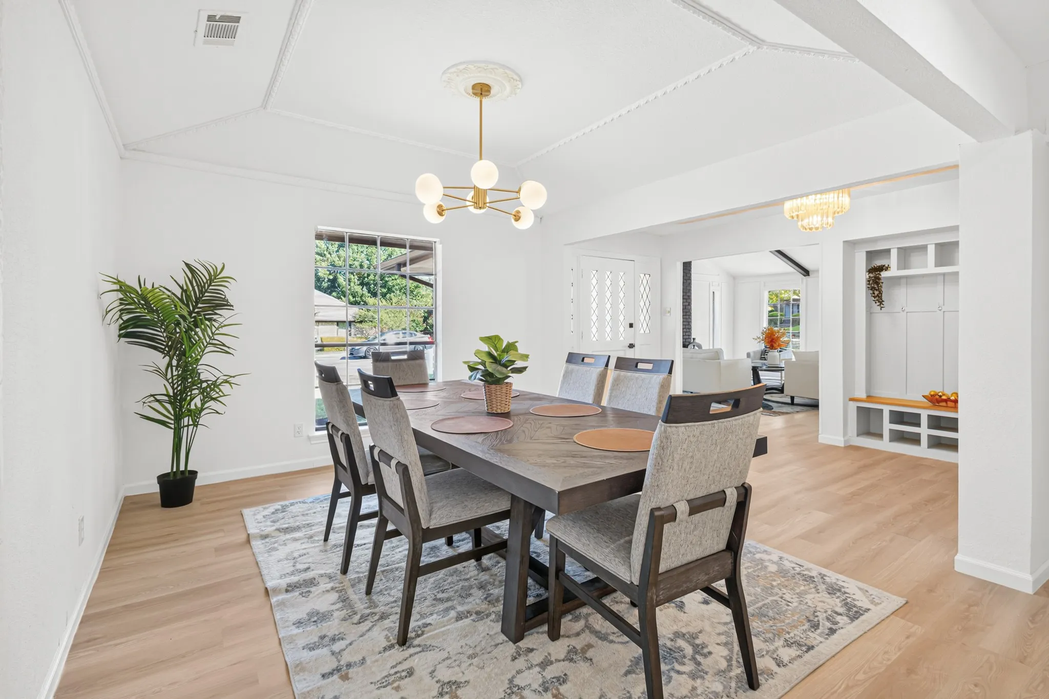 Open dining area showcasing wood-finish flooring, a wood dining table with seating for six, and a geometric area rug anchoring the space