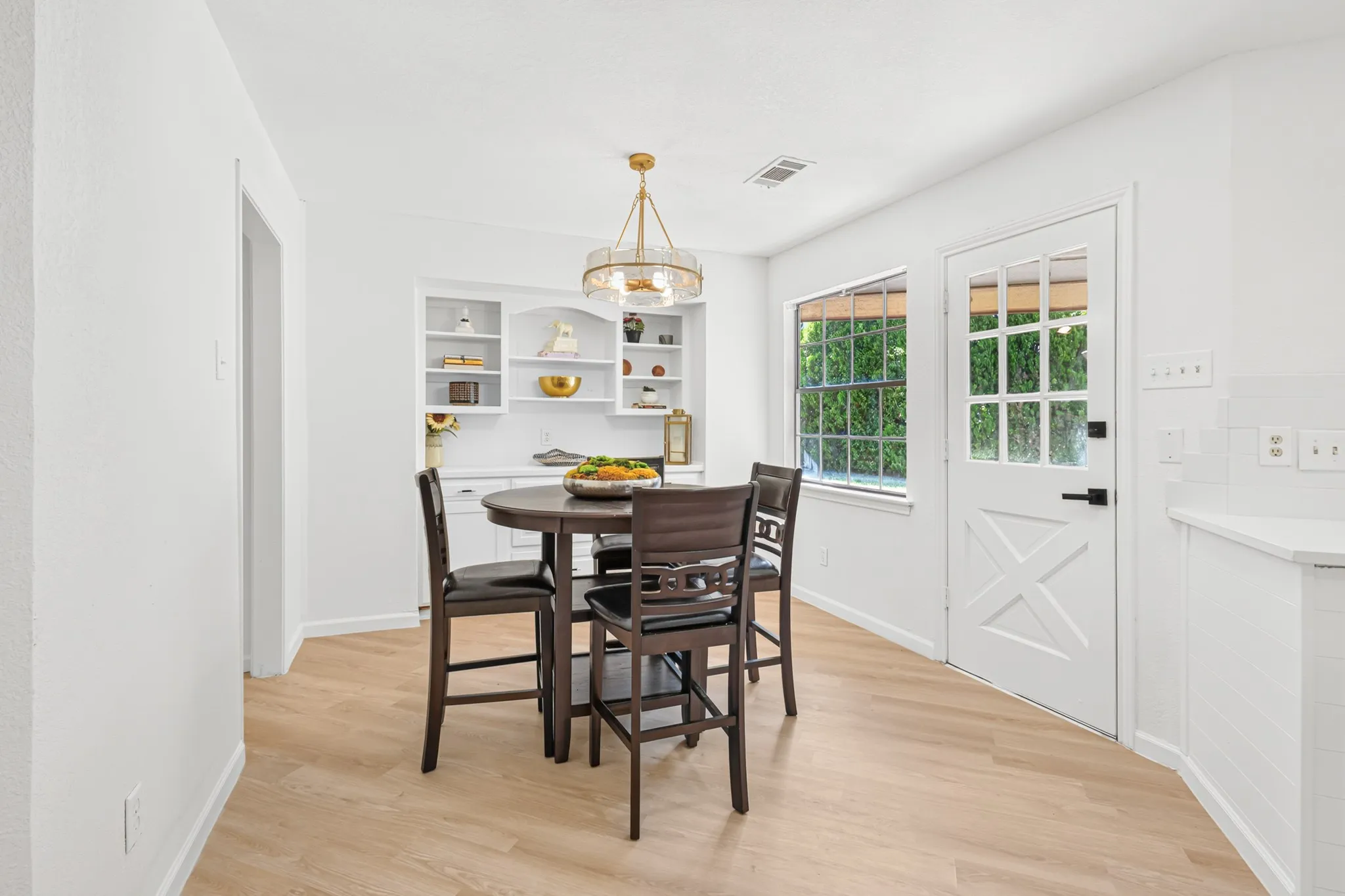 Wood-finish flooring, built-in shelving, a contemporary chandelier, a multi-pane window, and a paneled exterior door