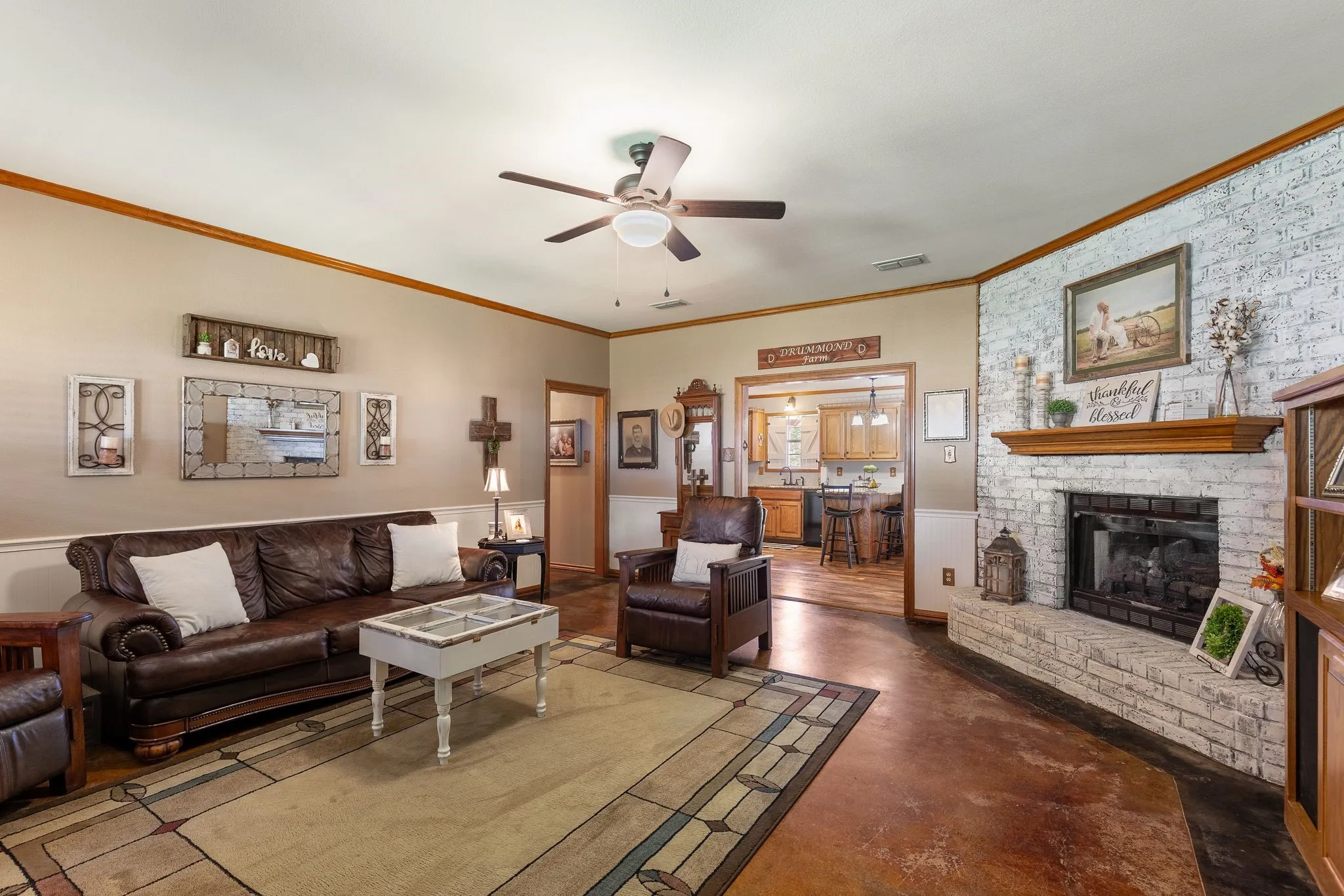 Living room with a brick fireplace, ceiling fan, and crown molding