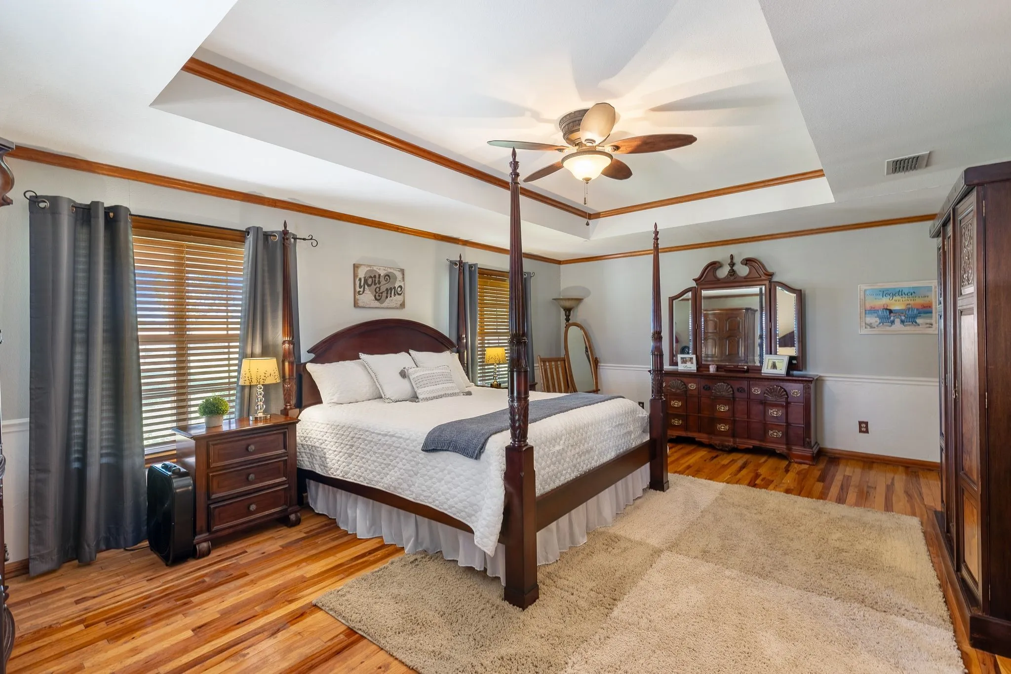 Bedroom with ceiling fan, crown molding, light hardwood / wood-style floors, and a raised ceiling