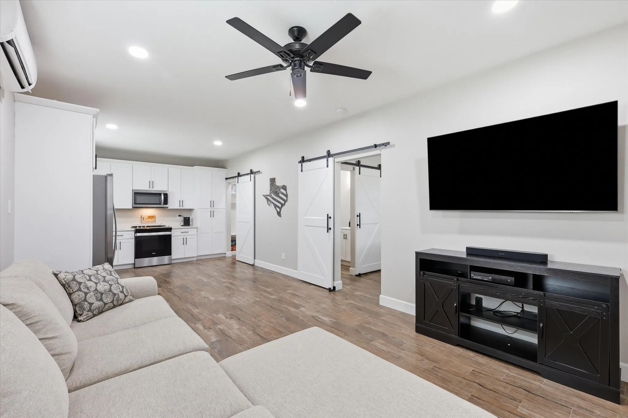 Open-concept living area featuring wood-finish flooring, recessed lighting, and a contemporary ceiling fan