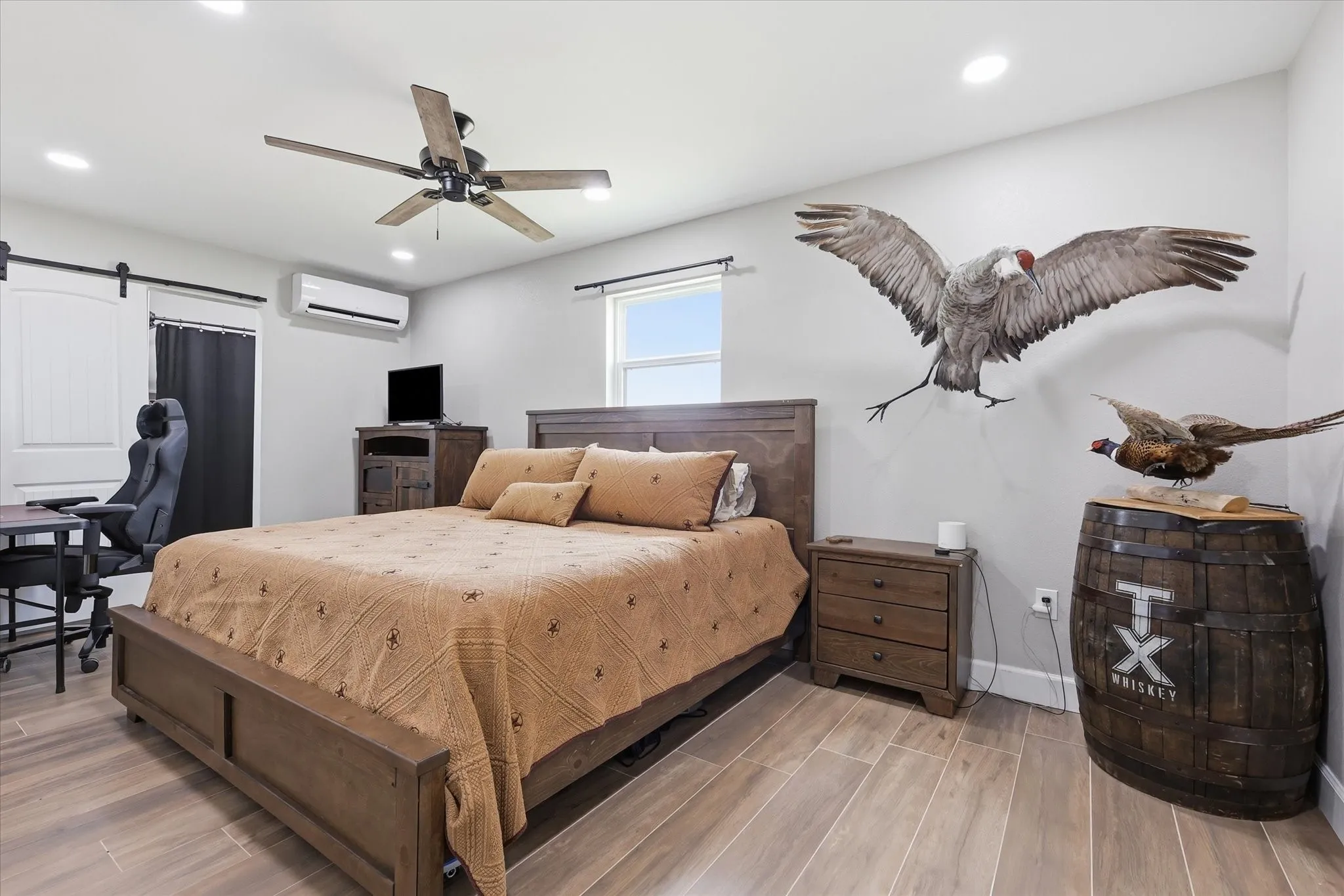 Spacious room featuring wood-finish flooring, a ceiling fan with integrated lighting, and a window providing natural light