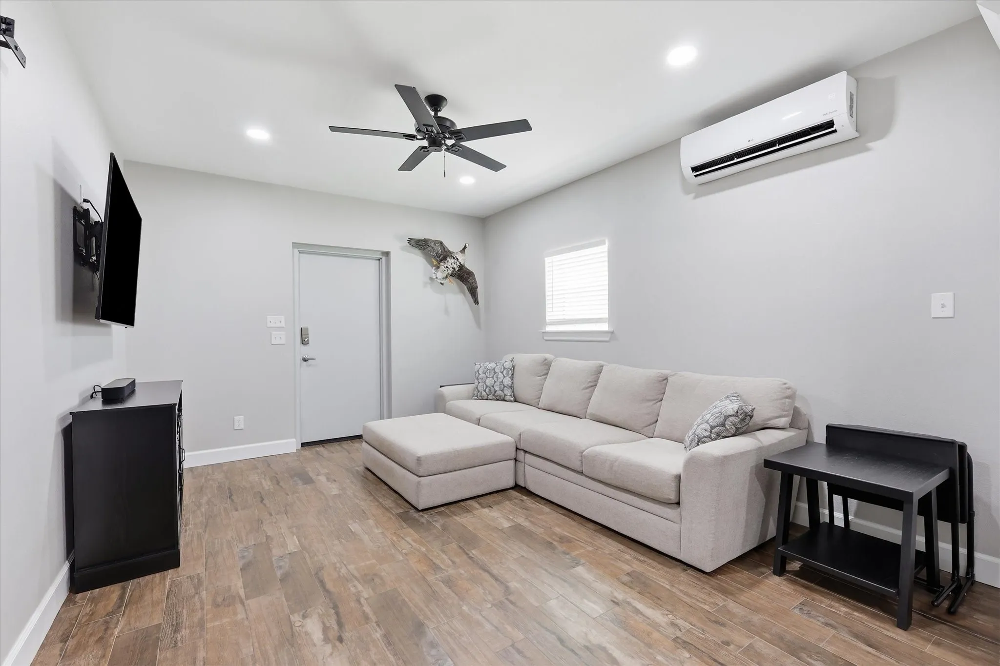 Living area featuring wood-finish flooring, recessed ceiling lighting, and a ceiling fan