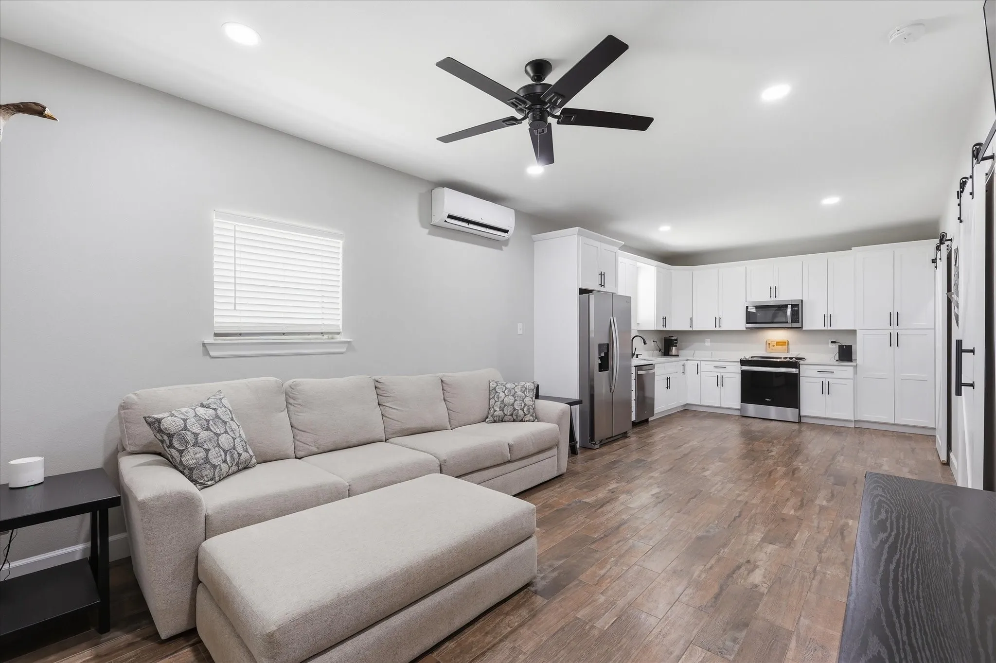 Open-concept living space featuring wood-finish flooring, recessed lighting, and a black ceiling fan