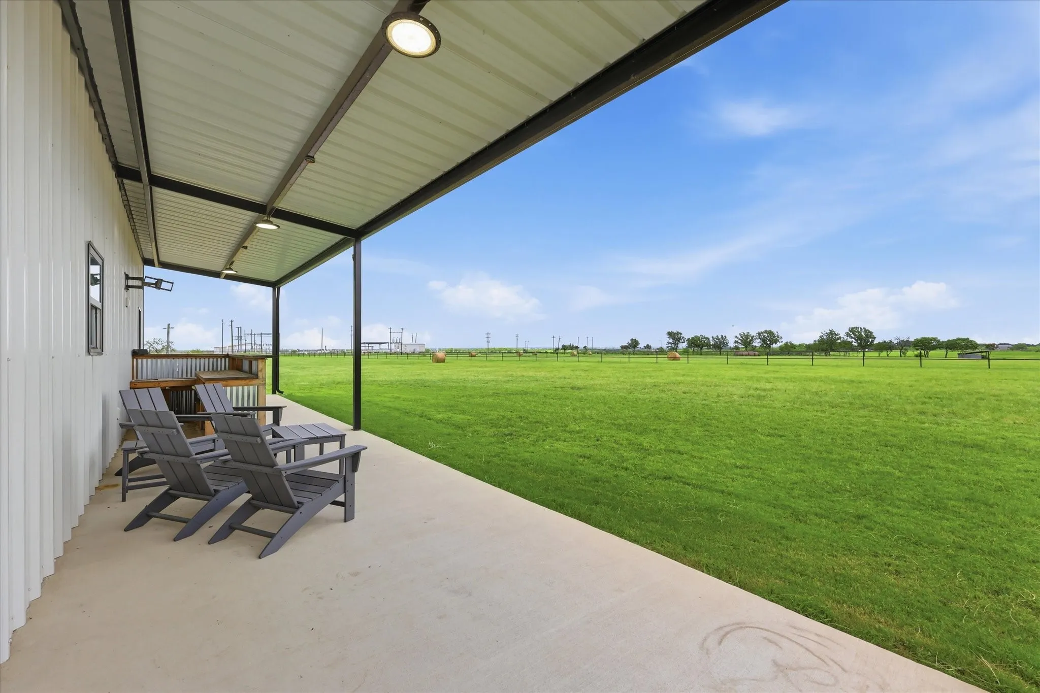 Spacious covered patio with a concrete floor, corrugated metal ceiling, and recessed lighting