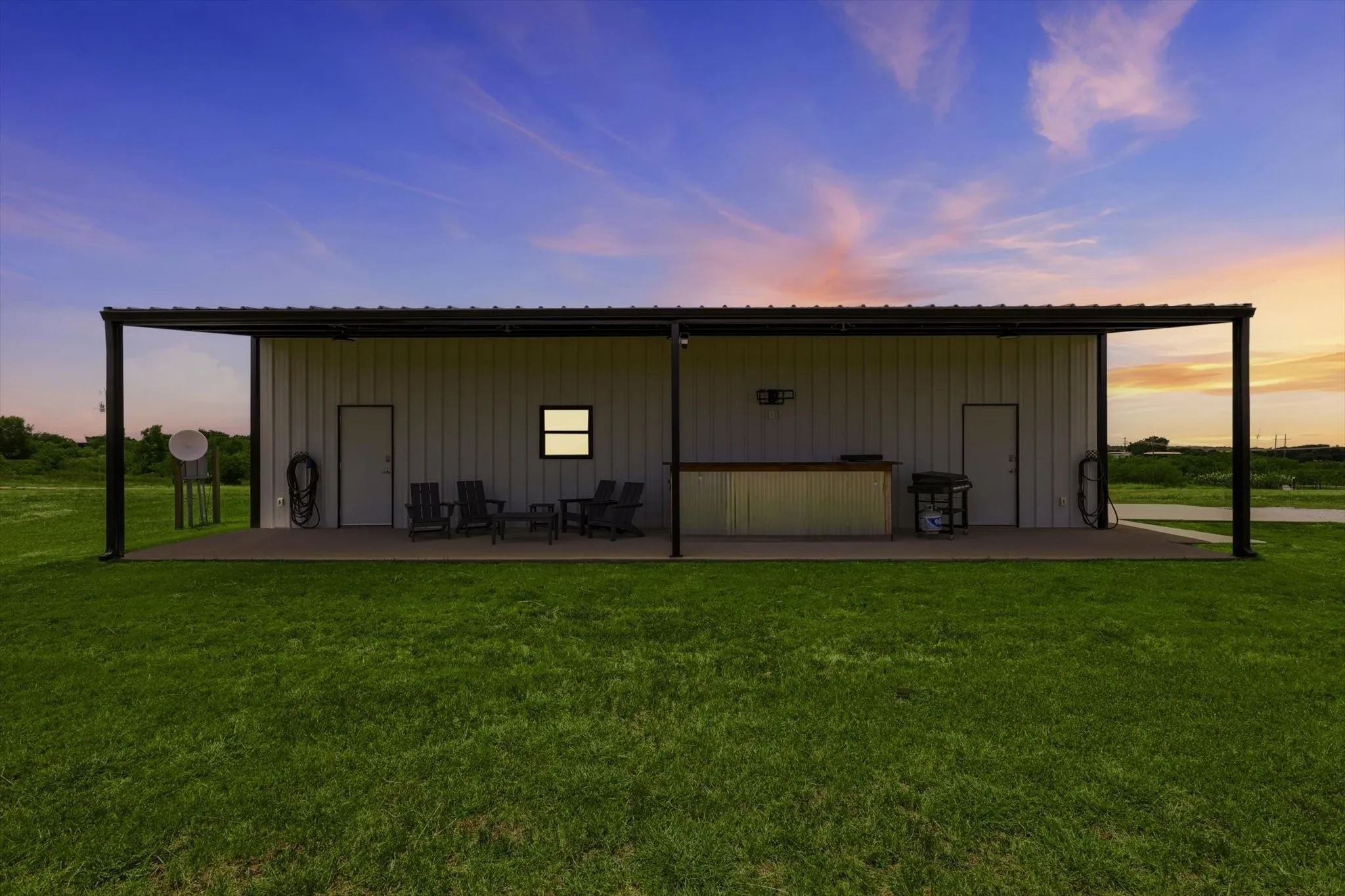 Steel structure with an extended covered patio, featuring a built-in counter area, exterior doors, and a small window