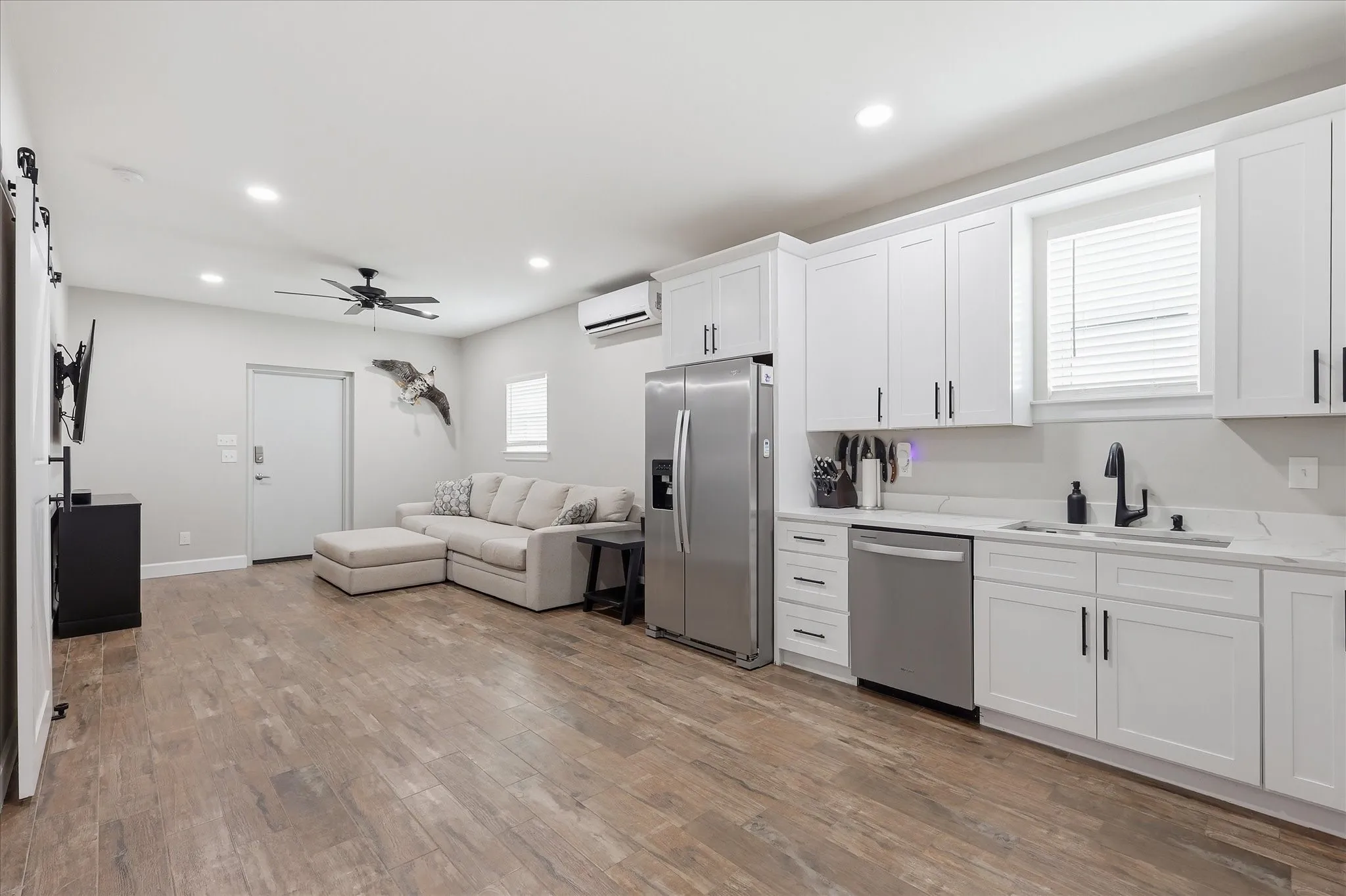 Open-concept living area featuring wood-finish flooring, recessed lighting, and a ceiling fan