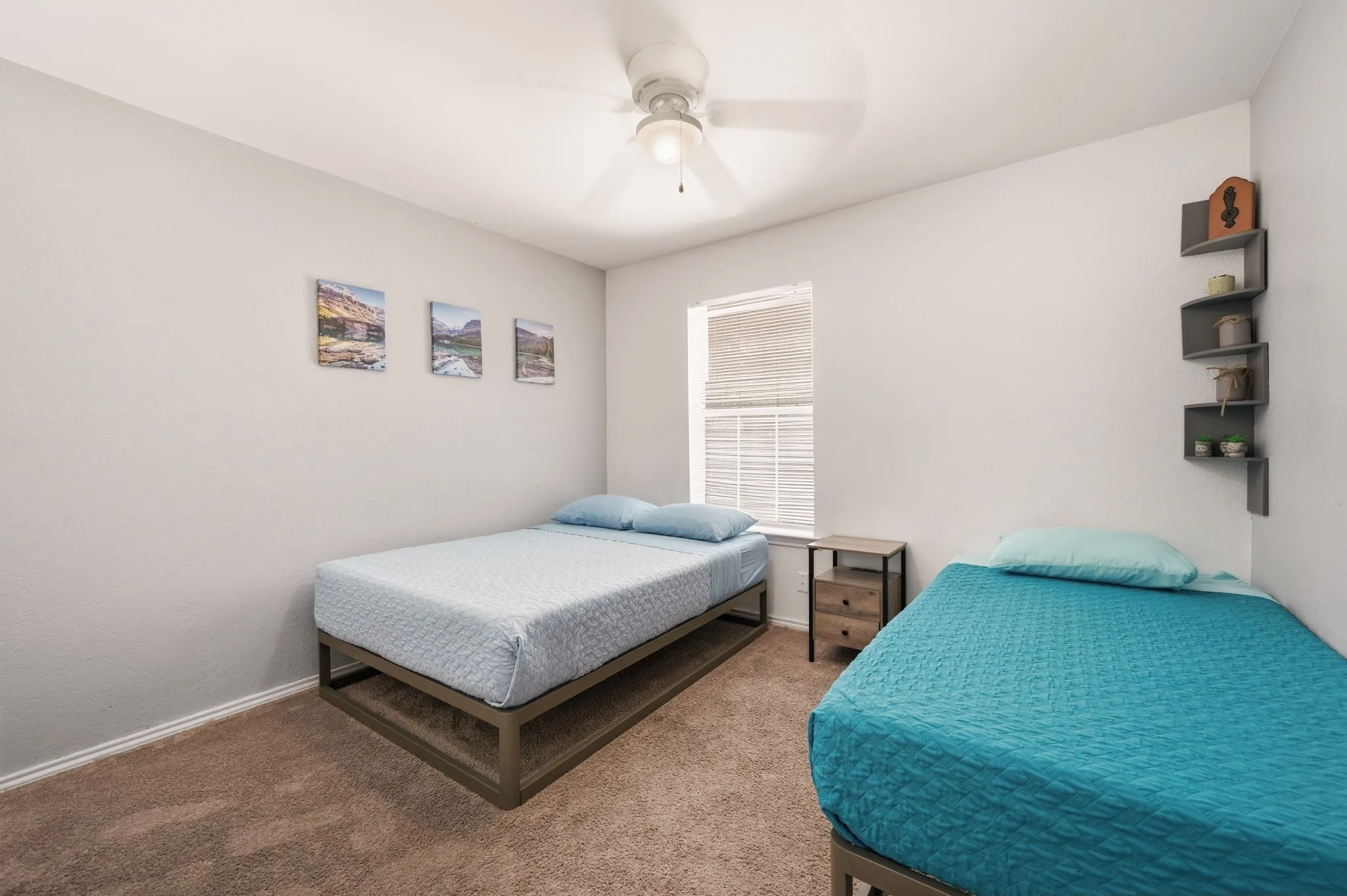 Carpeted room featuring a ceiling fan, a window with blinds, and built-in wall shelving