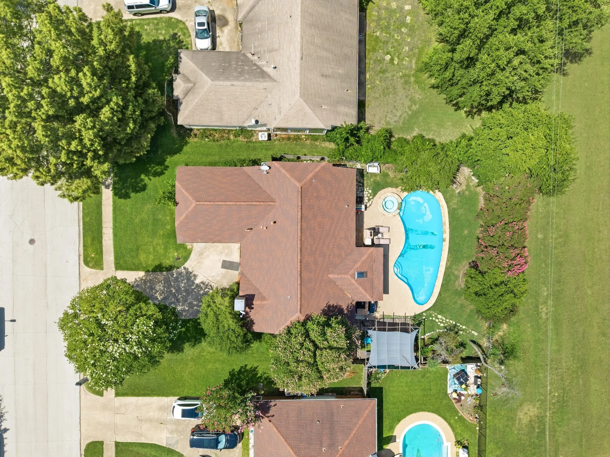 Aerial view of a residential property featuring a large freeform swimming pool with an integrated spa
