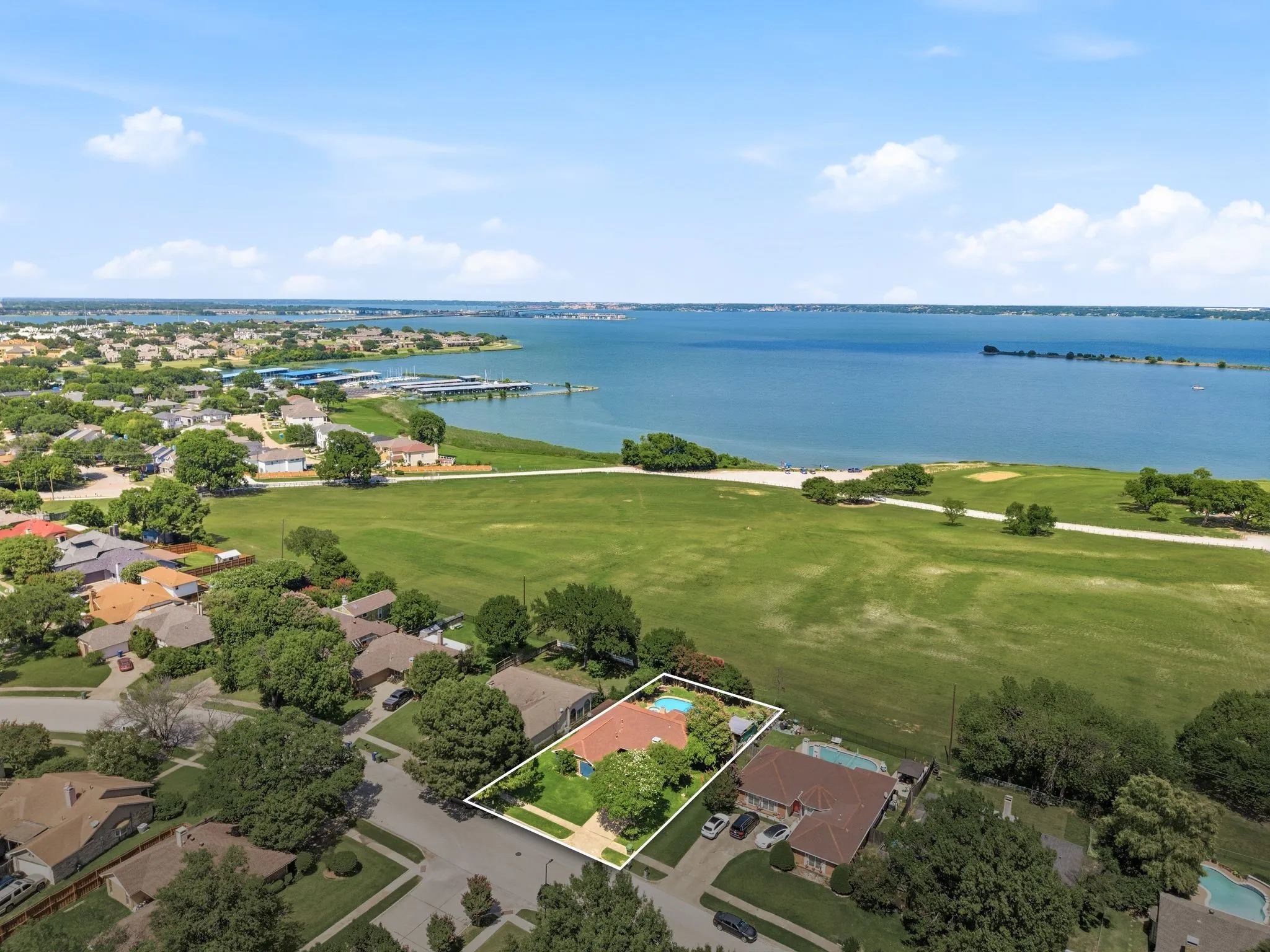 Residential property with a red tile roof and a backyard swimming pool, situated near a large body of water