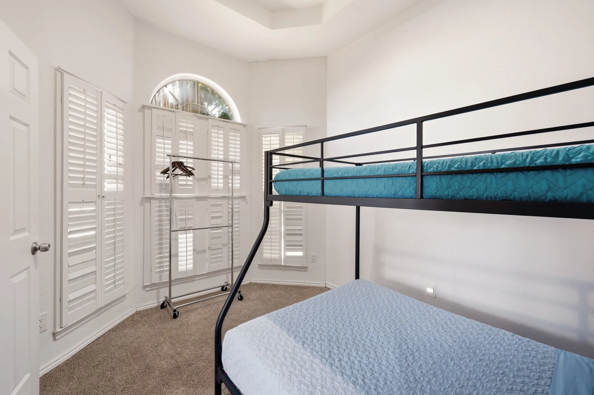 Room featuring white walls, carpet flooring, and a tray ceiling