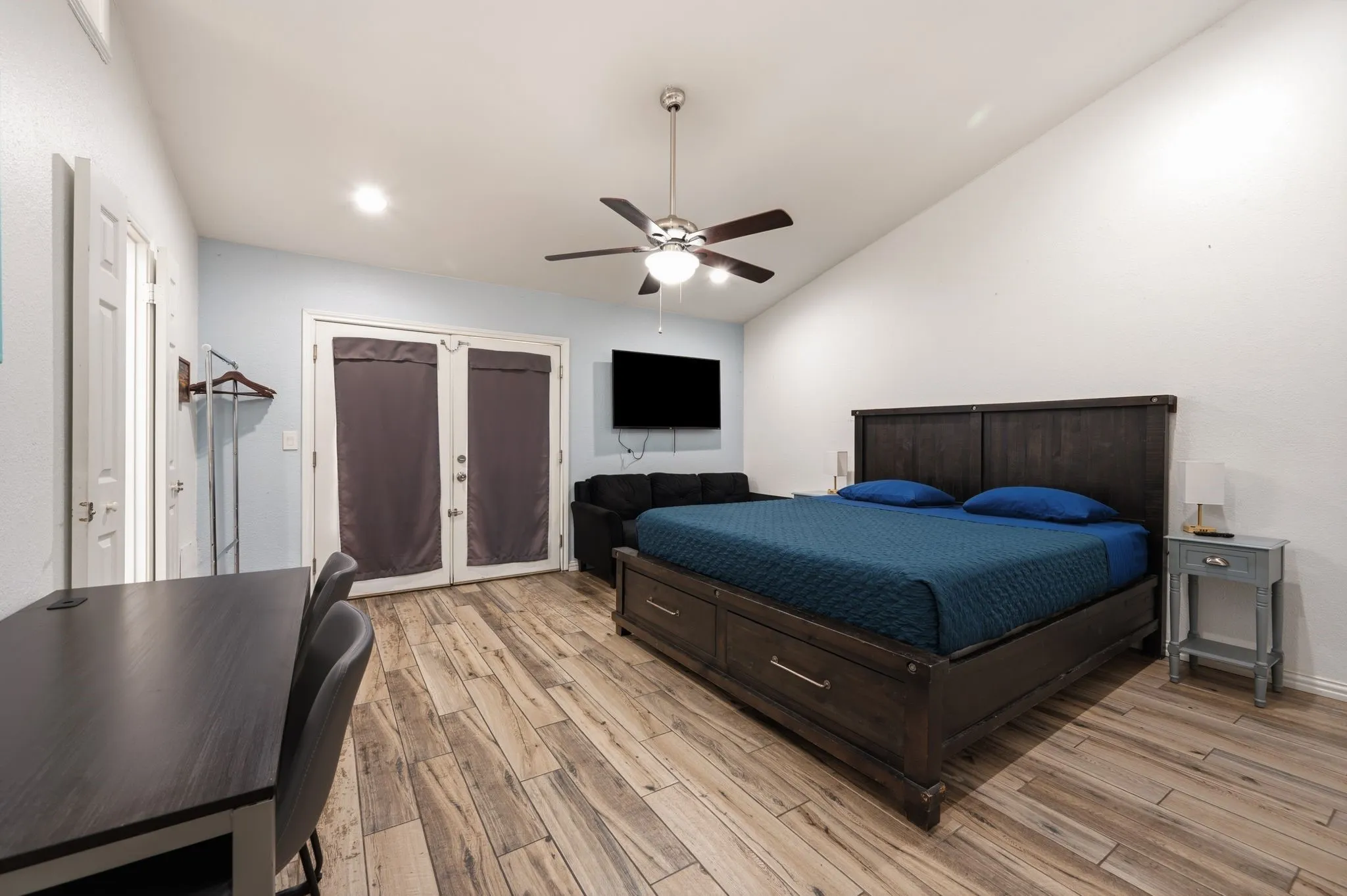Spacious room featuring vaulted ceilings, wood-finish flooring, and a ceiling fan