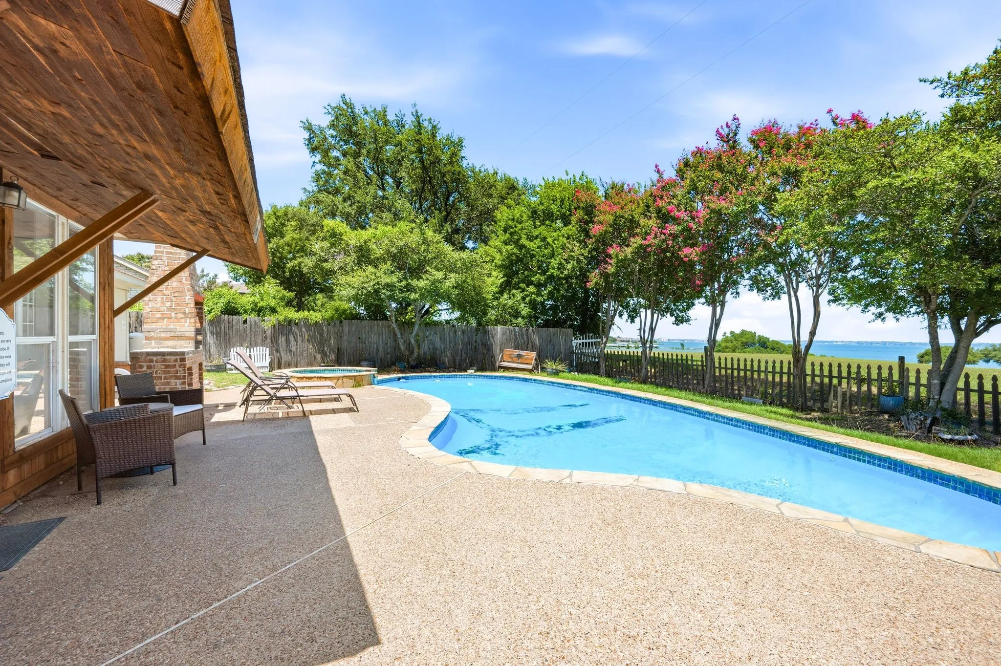 Freeform swimming pool with an integrated hot tub, surrounded by an exposed aggregate patio