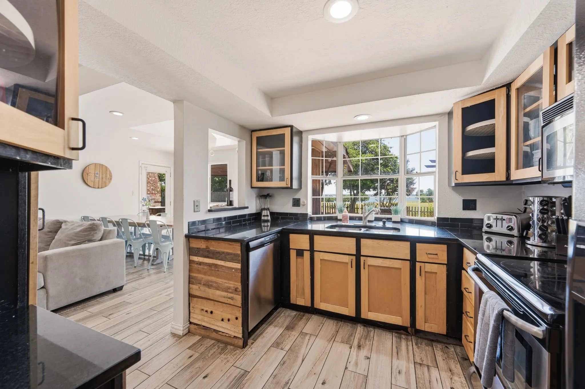 Kitchen featuring wood-finish flooring, dark countertops, and light wood cabinetry with dark accents