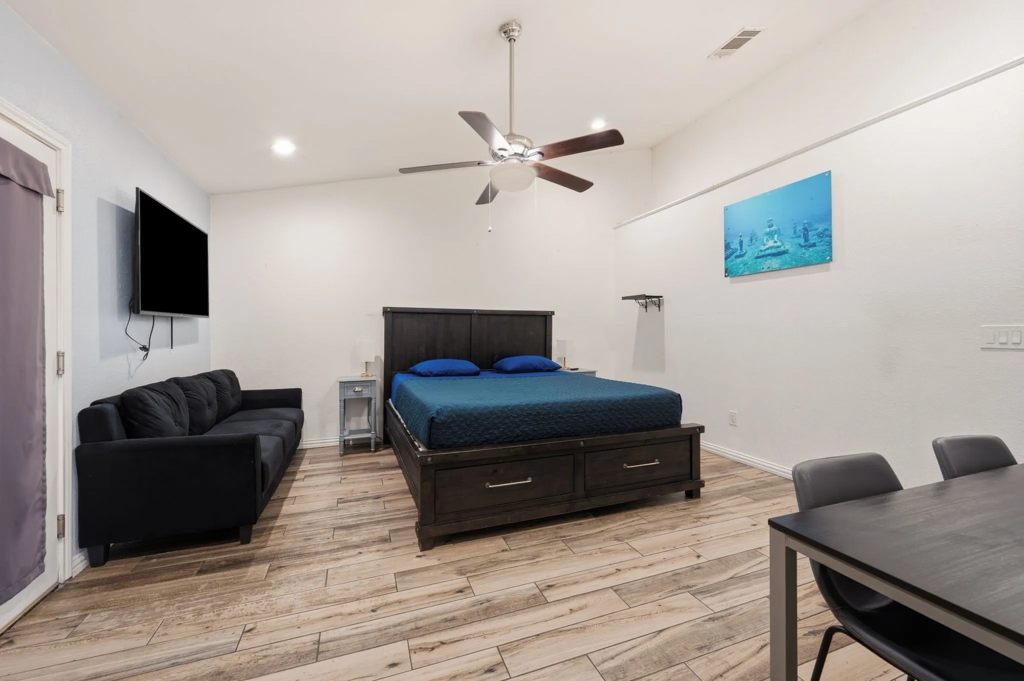 Spacious room featuring wood-finish flooring, a ceiling fan, recessed lighting, and white walls