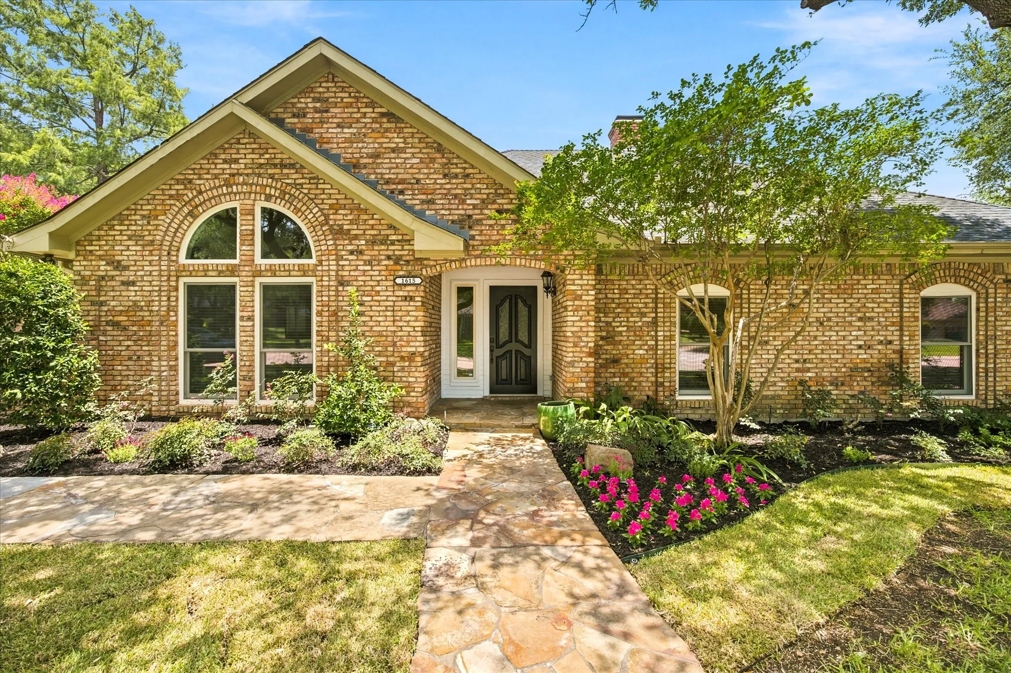 Brick facade residence featuring a stone pathway leading to a double-entry front door