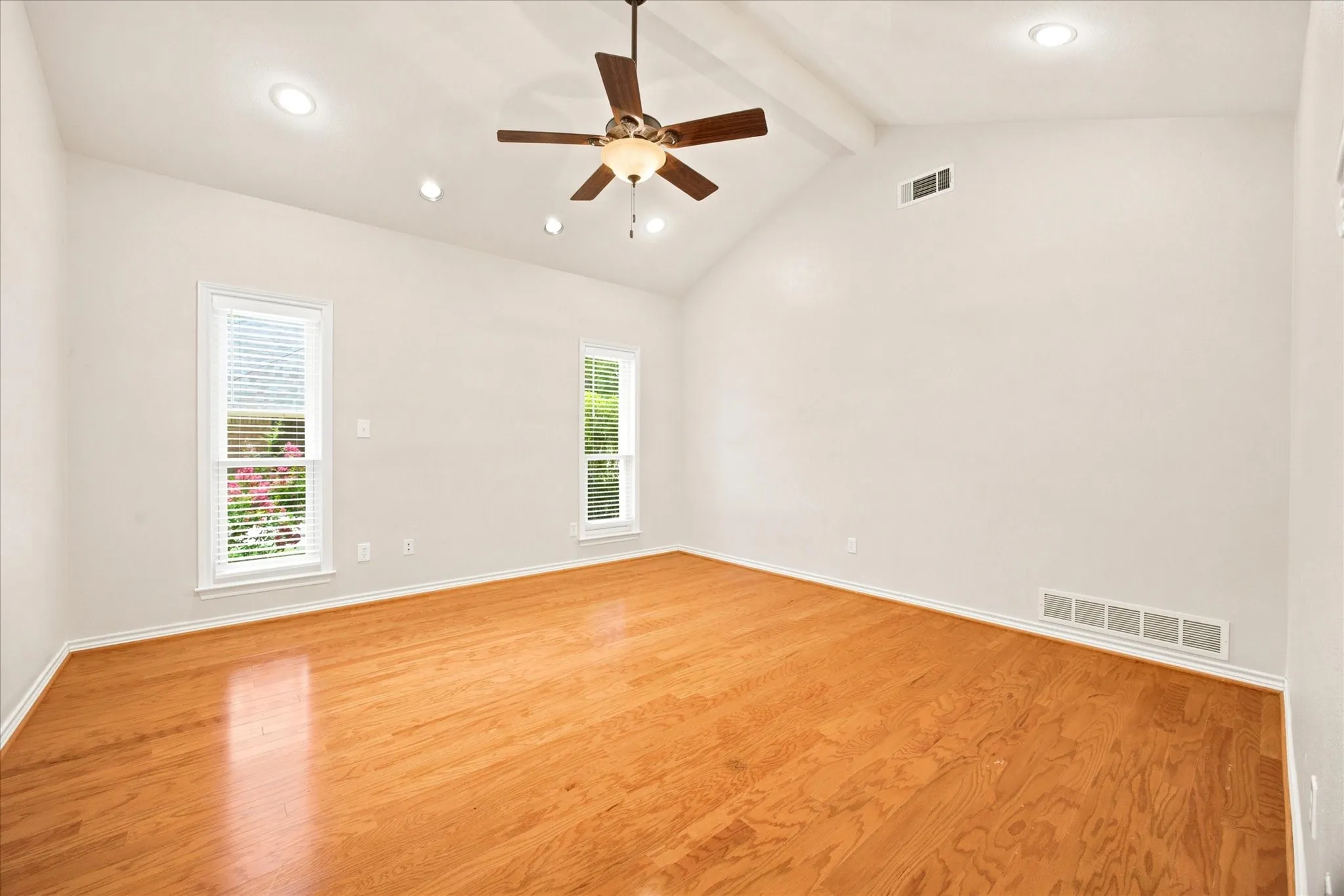 Spacious room featuring vaulted ceilings, wood-finish flooring, recessed lighting, and a ceiling fan