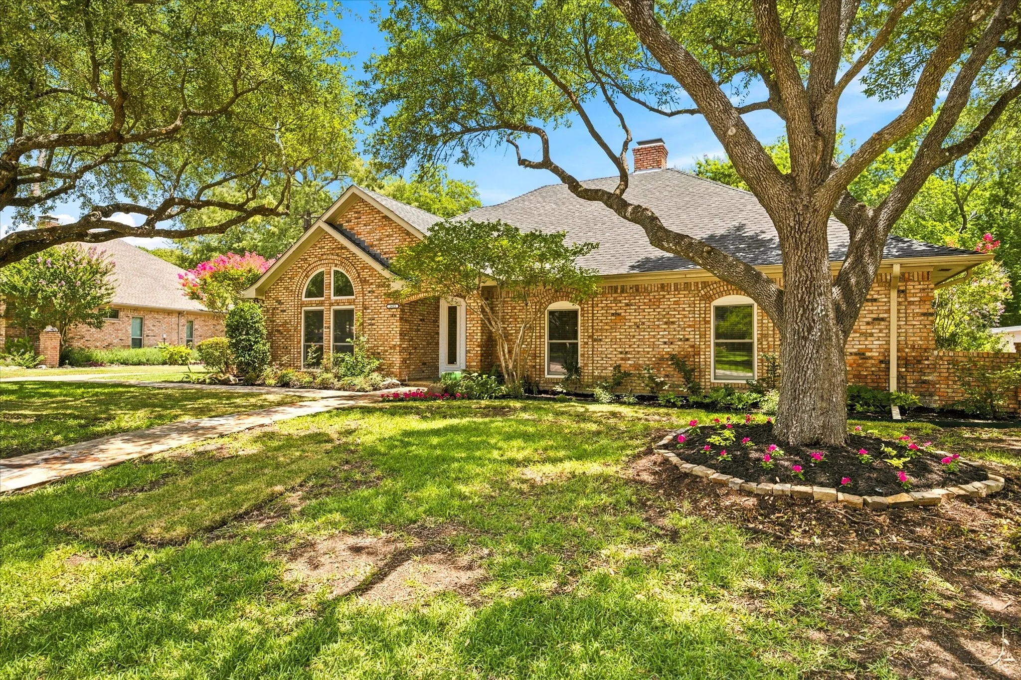 Brick exterior with arched window detailing, surrounded by mature trees