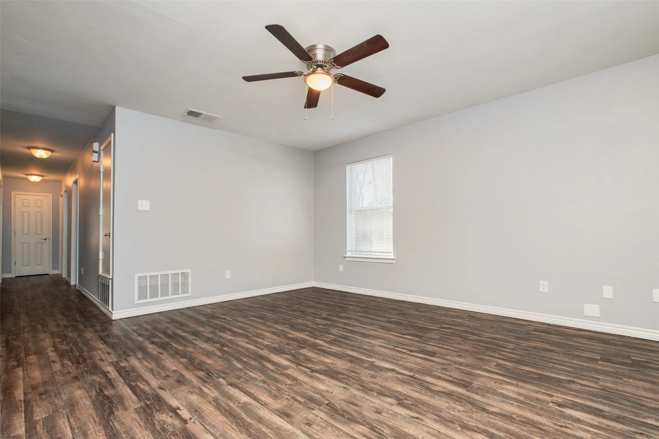Spacious room featuring wood-finish flooring, light gray wall paint, and white trim