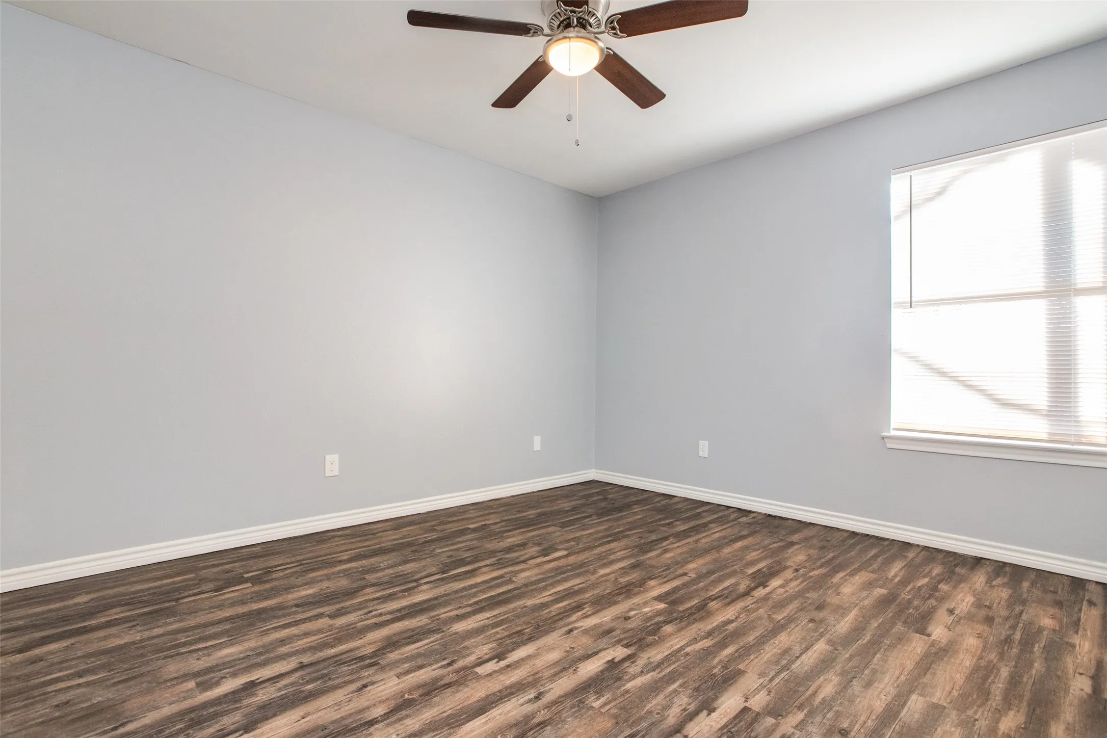 Room featuring wood-finish flooring, light grey wall paint, and white baseboards