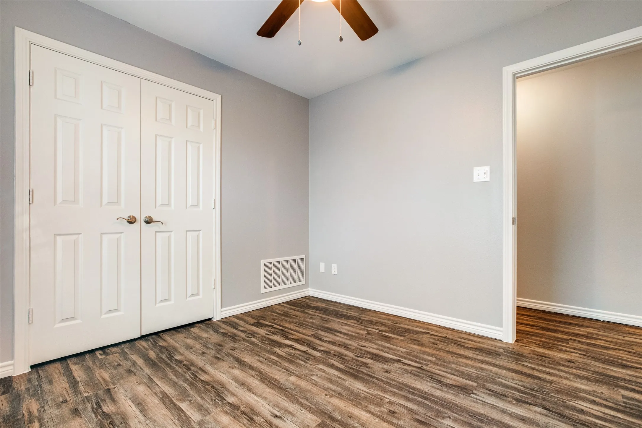 Interior space featuring wood-finish flooring, light gray walls, white baseboards, and a ceiling fan