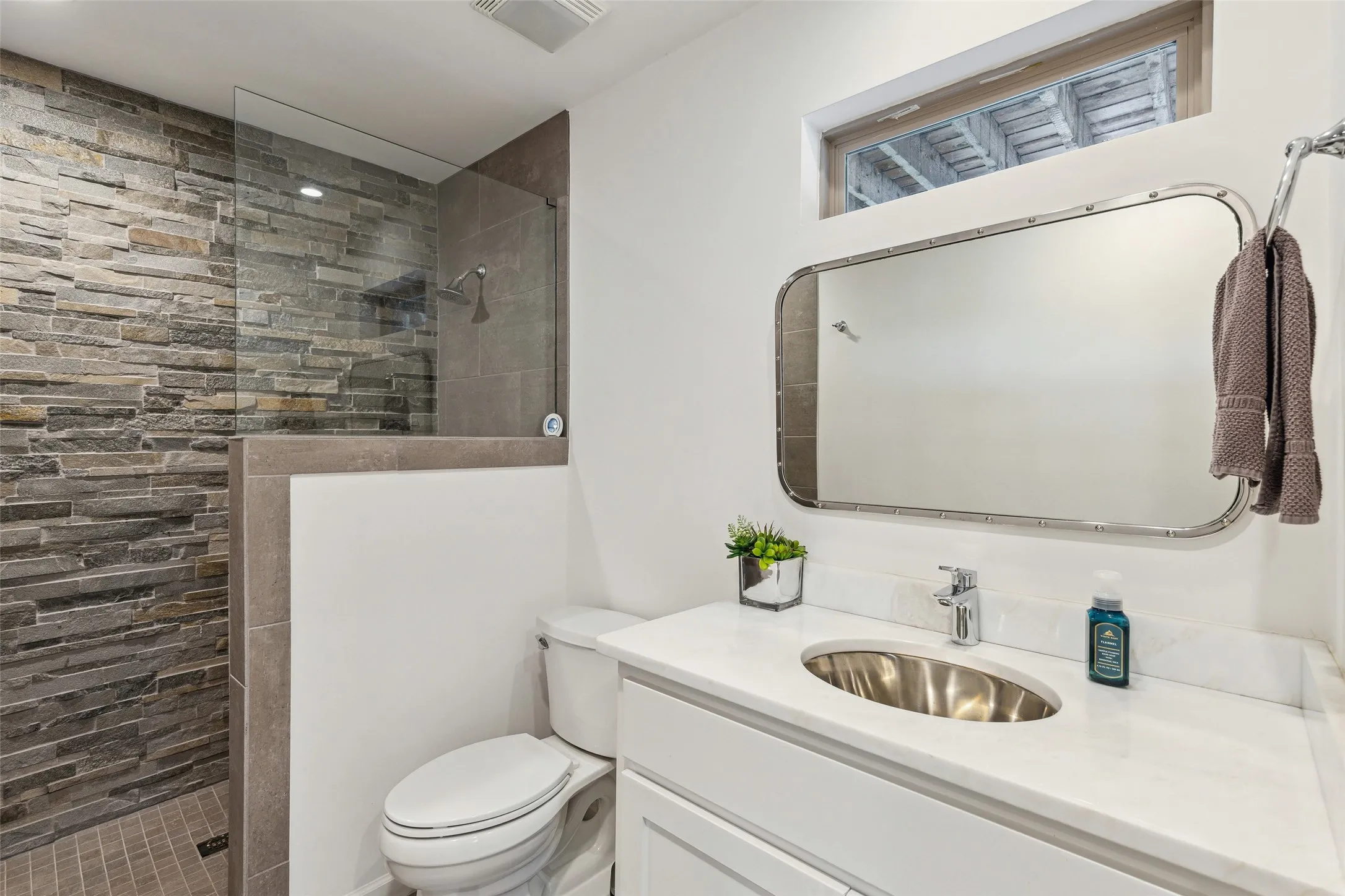 Bathroom with tiled shower, toilet, and large vanity
