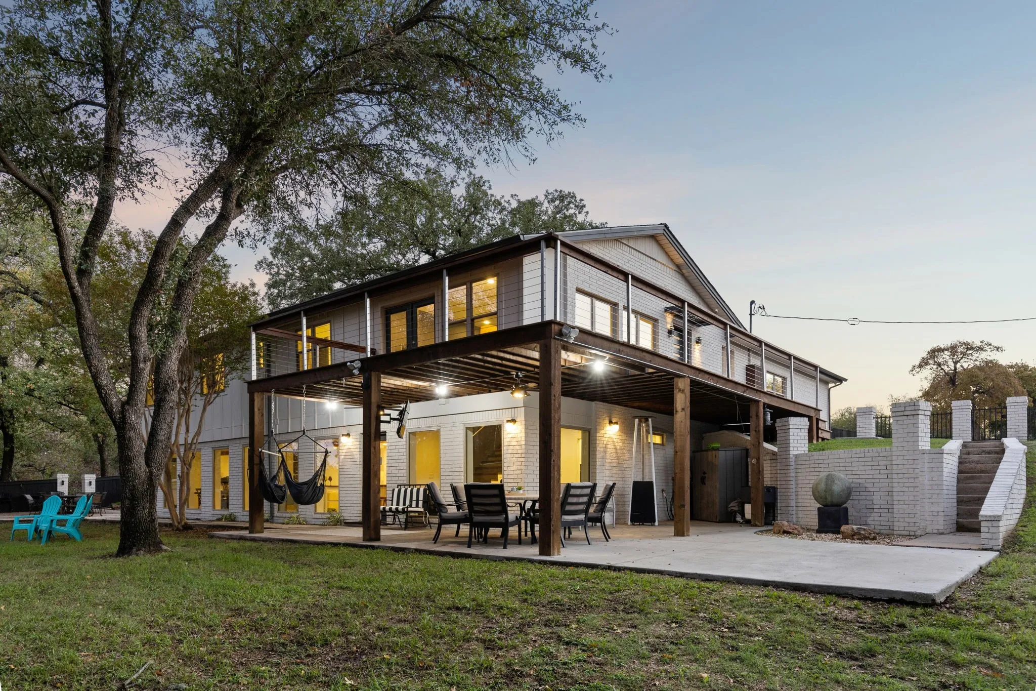 Back house at dusk featuring covered batio, upstairs deck and zen garden
