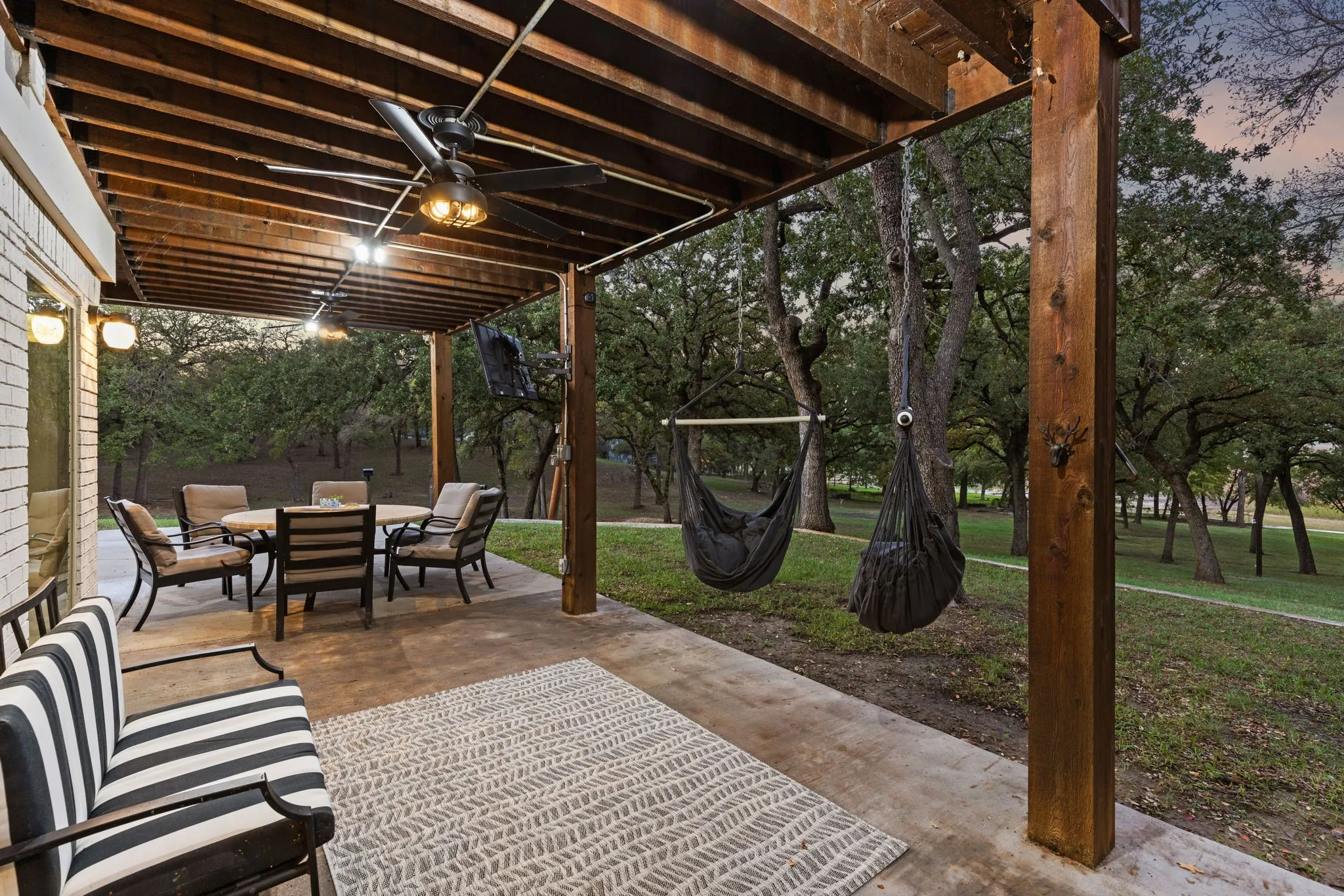 Patio terrace at dusk with ceiling fan and a yard