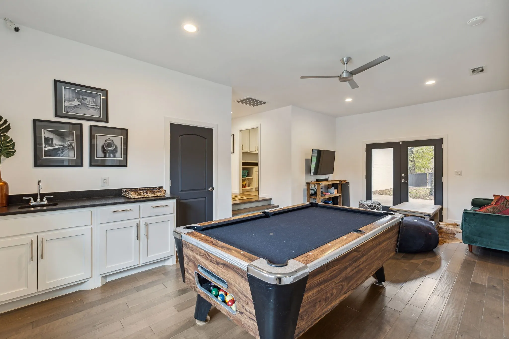 Game room features a wet bar, a celing fan and double doors that open into the courtyard