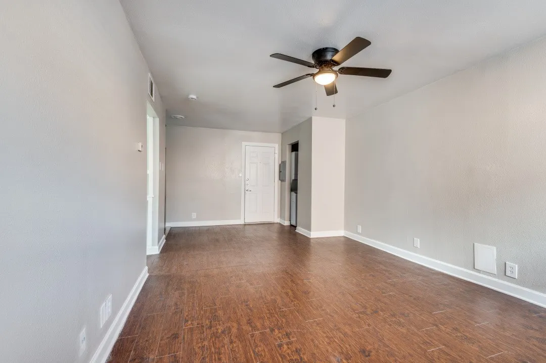Spacious interior featuring wood-finish flooring, light grey wall paint, and white baseboards
