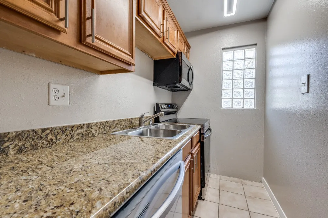 Kitchen featuring wood cabinetry, granite-finish countertops, and a double basin stainless steel sink