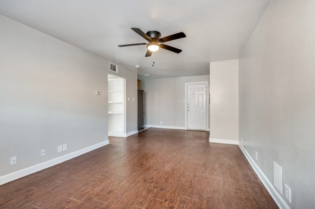 Expansive living area with wood-finish flooring, light gray walls, and white baseboards