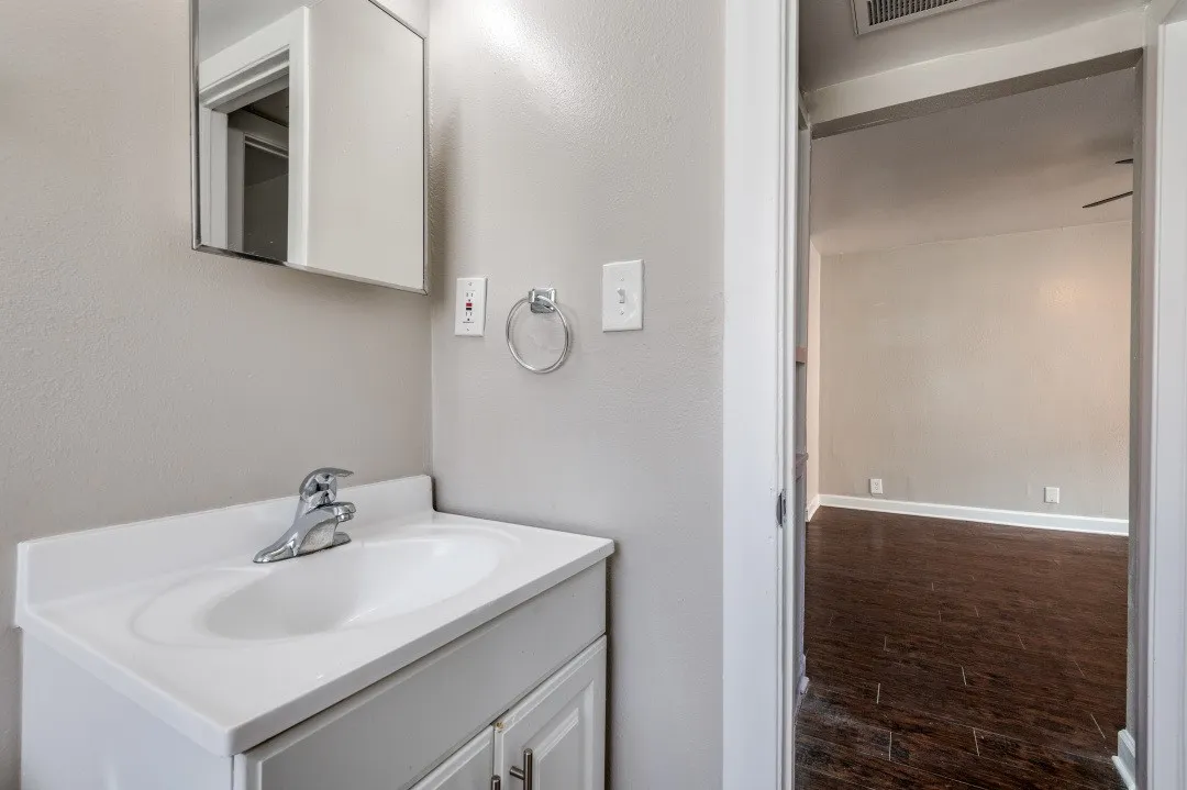 Bathroom vanity with integrated sink, chrome faucet, and mirrored medicine cabinet