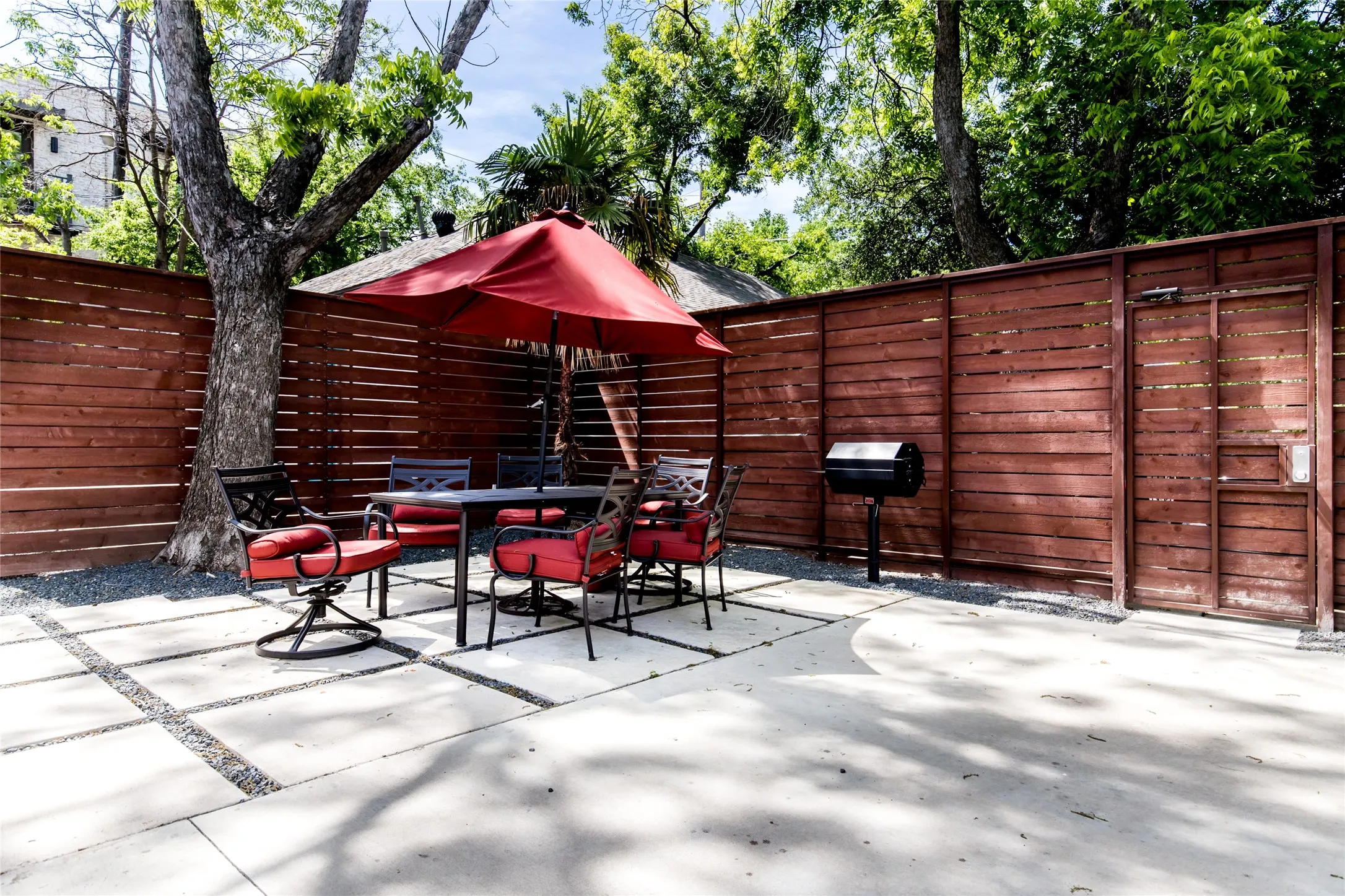 Outdoor patio area featuring a concrete surface with decorative stone inlay, bordered by a horizontal slat wood fence
