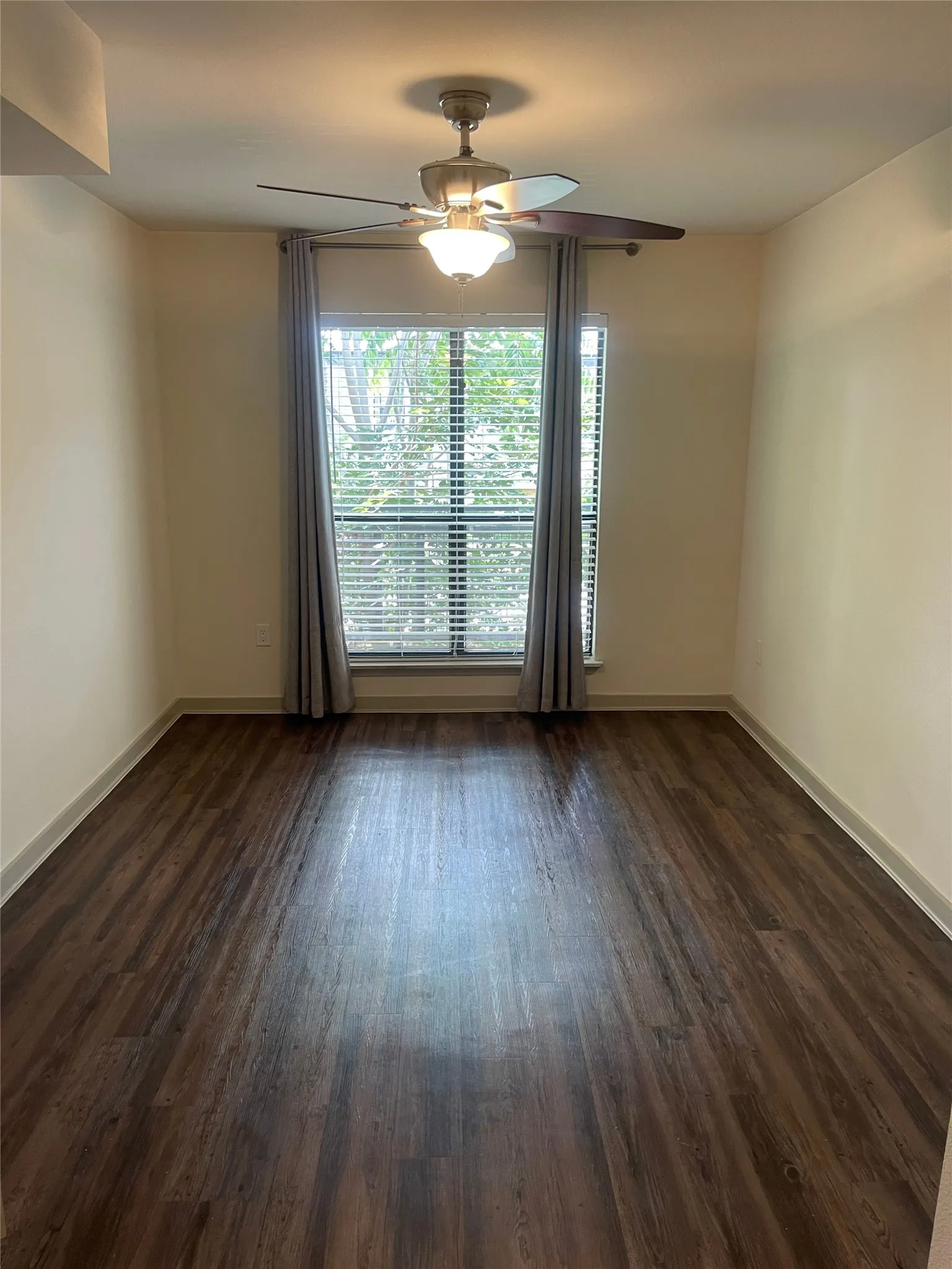 Room featuring wood-finish flooring, a window with horizontal blinds, and a ceiling fan with integrated lighting