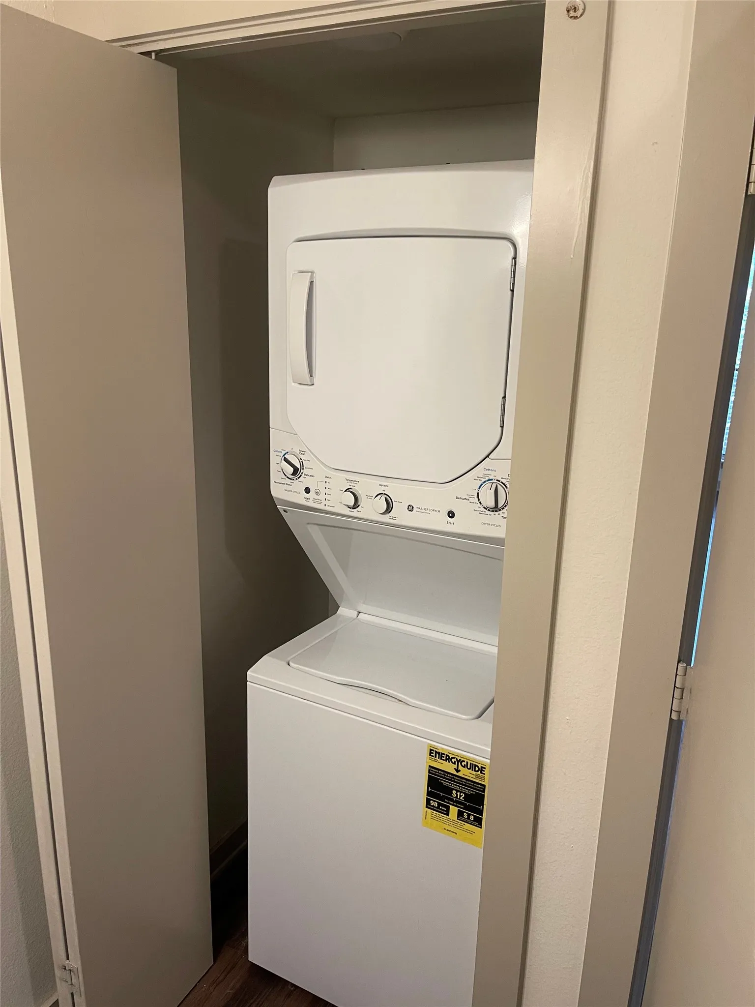 Built-in laundry closet featuring a white stacked washer and dryer unit