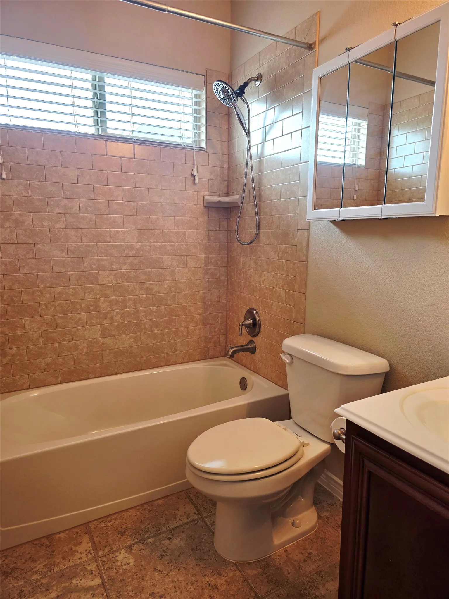 Tub and shower combination with subway tile surround, window with blinds, and white medicine cabinet