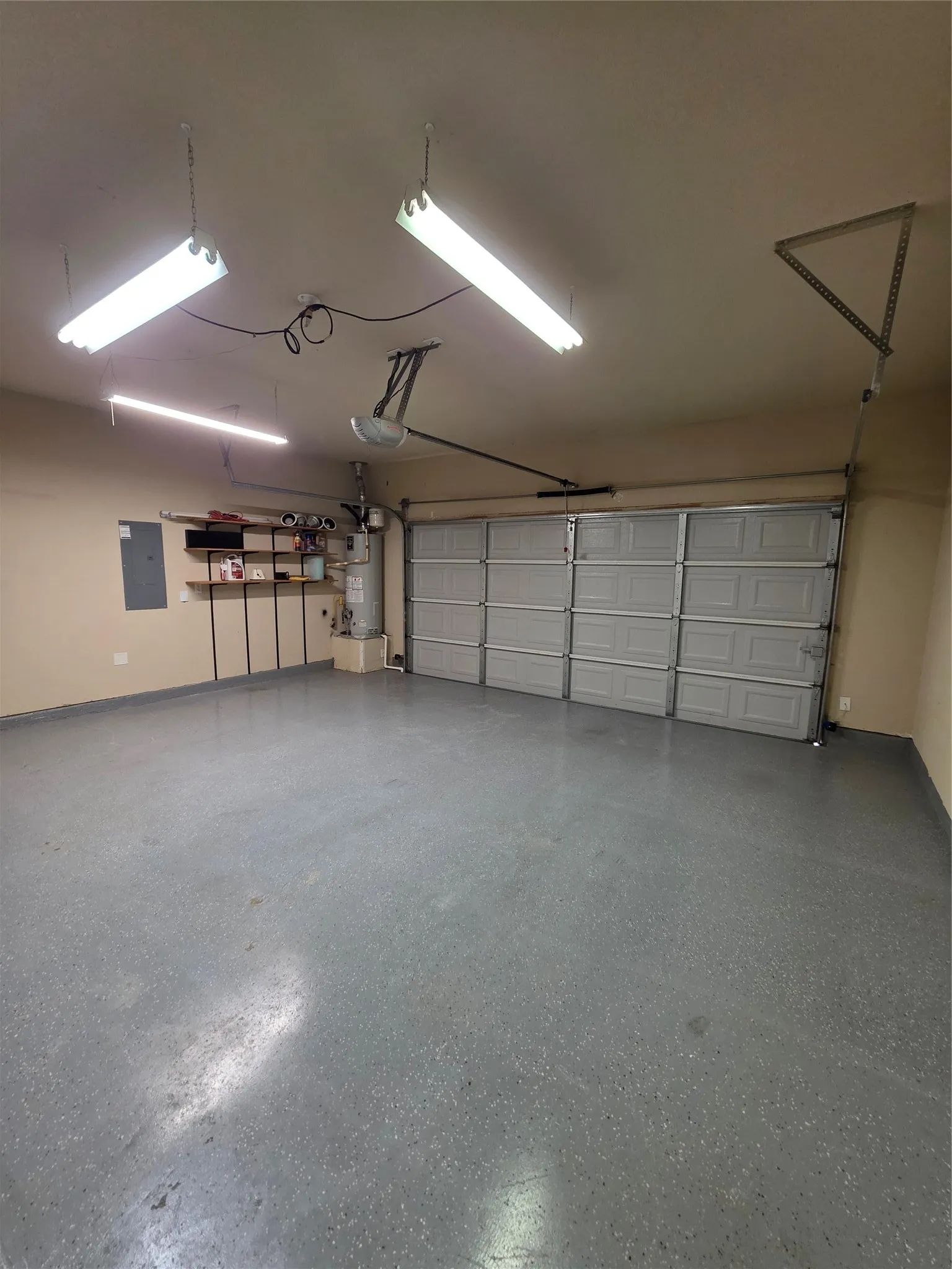 Spacious garage featuring a finished floor coating, fluorescent overhead lighting, and built-in wall shelving
