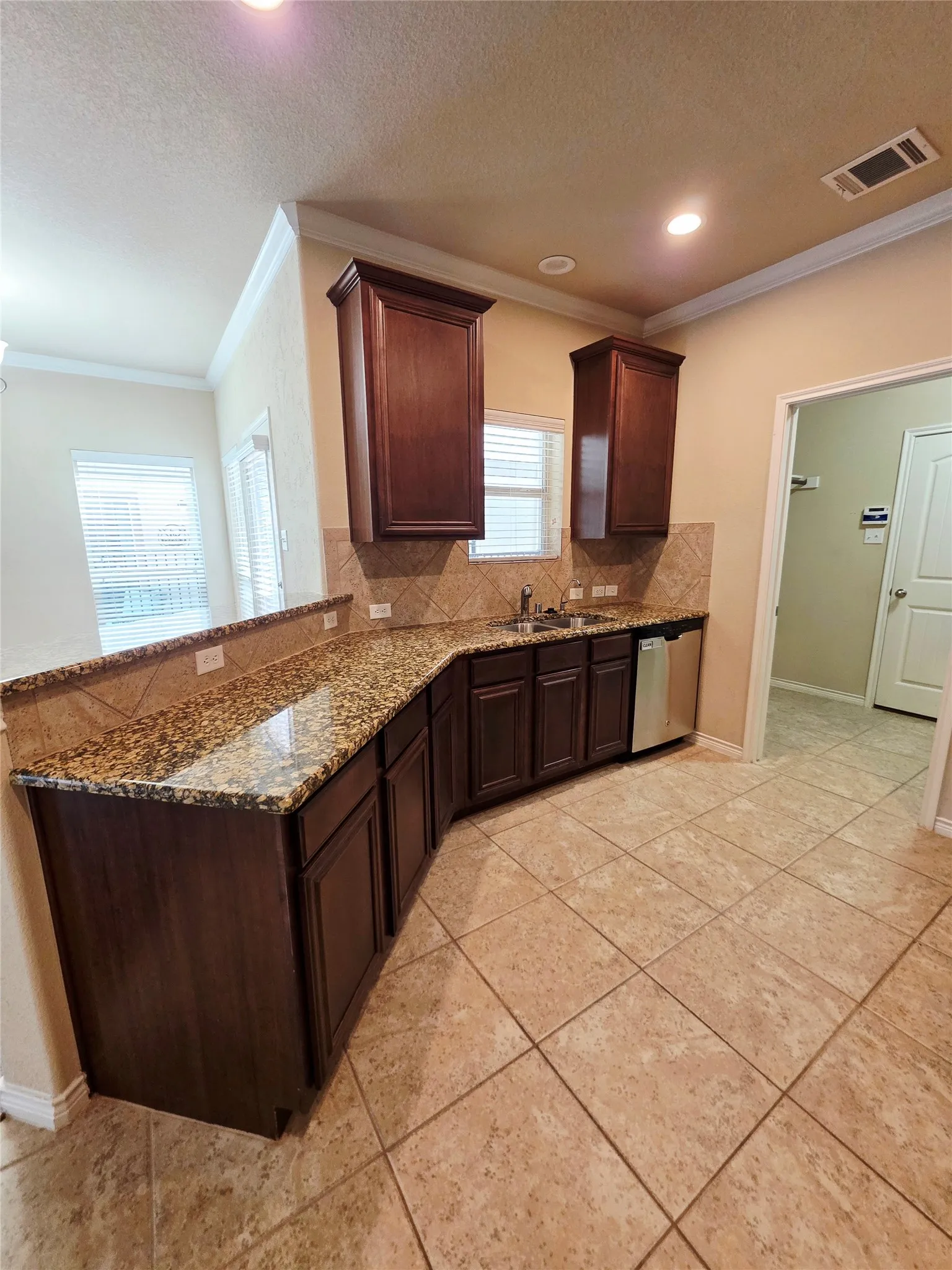 Kitchen featuring granite countertops, dark wood-finish cabinetry, tile flooring, and a tile backsplash
