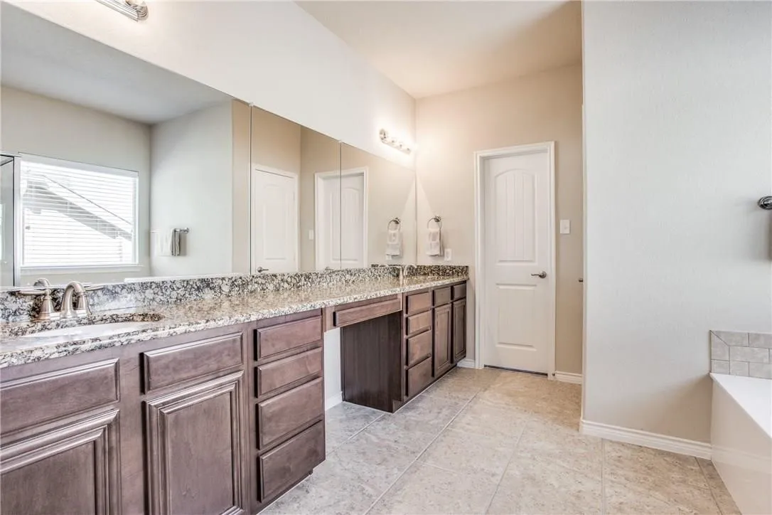 Spacious bathroom featuring an extended vanity with dual sinks, granite countertops, and dark wood cabinetry