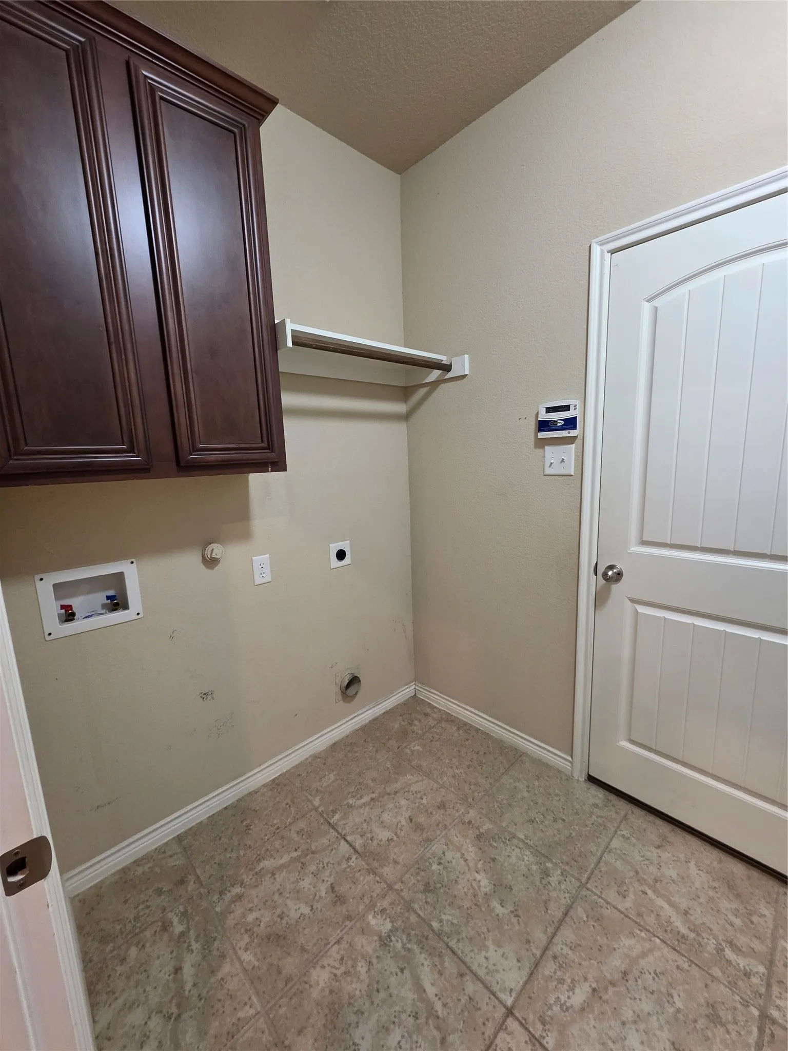 Built-in cabinetry, wall-mounted hanging rod, tile flooring, and a paneled door