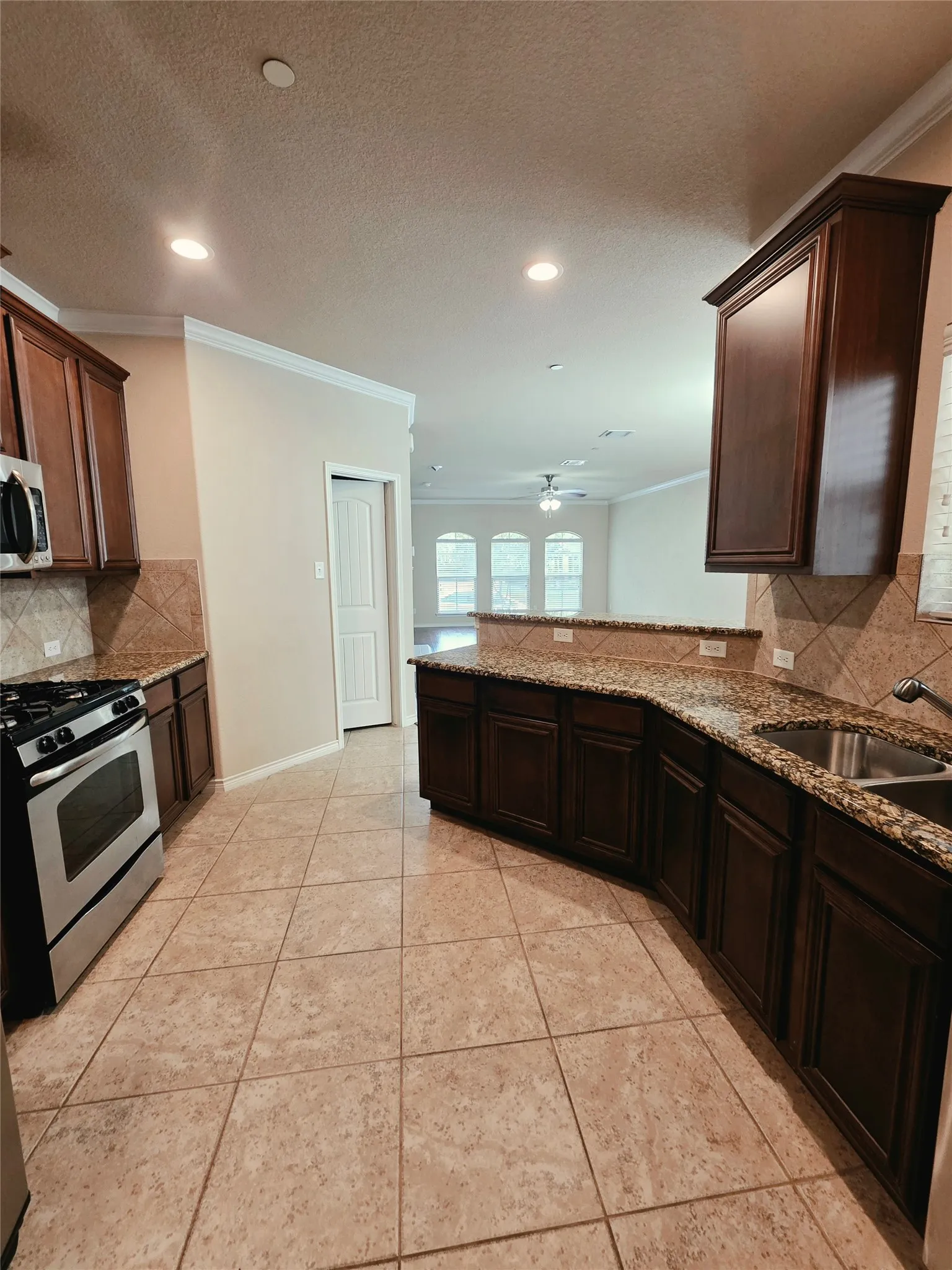 Kitchen featuring dark wood-finish cabinetry, tile flooring, and granite countertops
