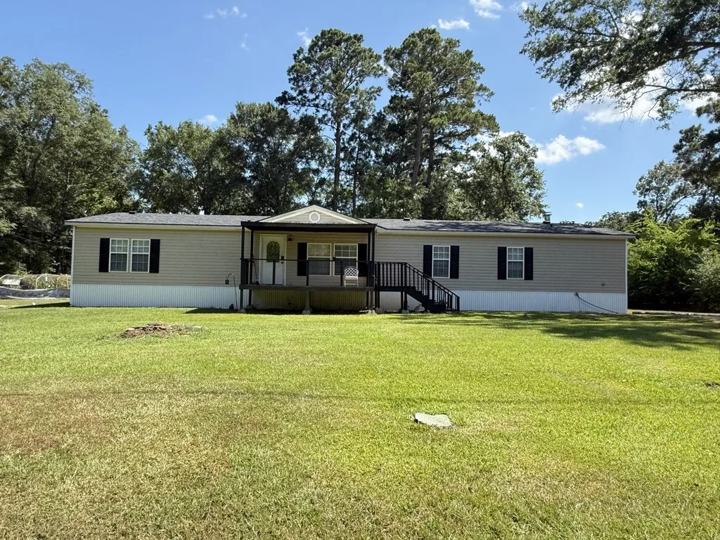 Single-story residence featuring light-colored siding, a covered front porch with dark railings, and a dark shingle roof