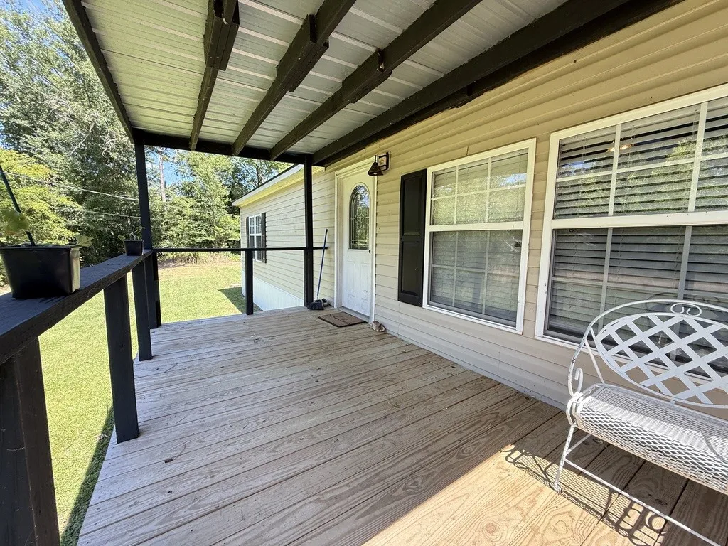 Wood-finish porch decking with a black railing system and light beige siding