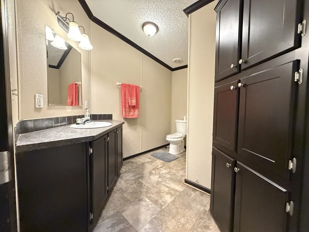 Bathroom featuring a vanity with dark cabinetry, an integrated sink, and a framed mirror