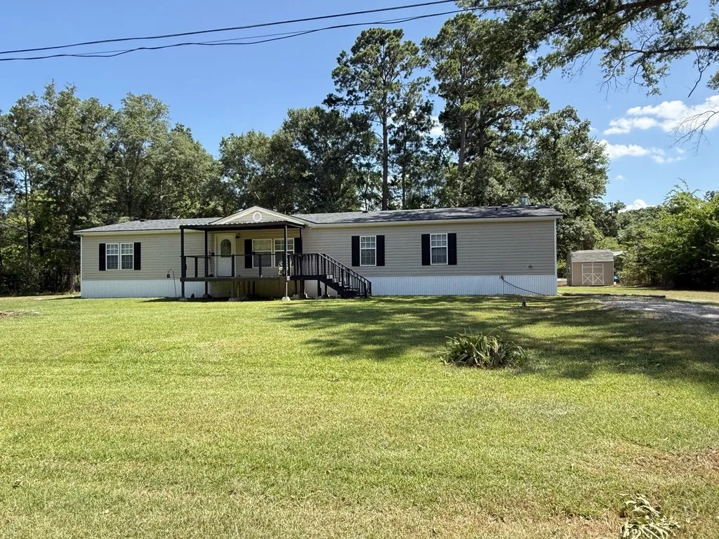 Single-story residence featuring light-colored siding, black shutters, and a covered porch entry