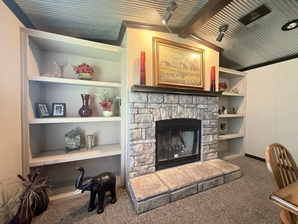 Stone-clad fireplace with hearth, flanked by built-in bookshelves