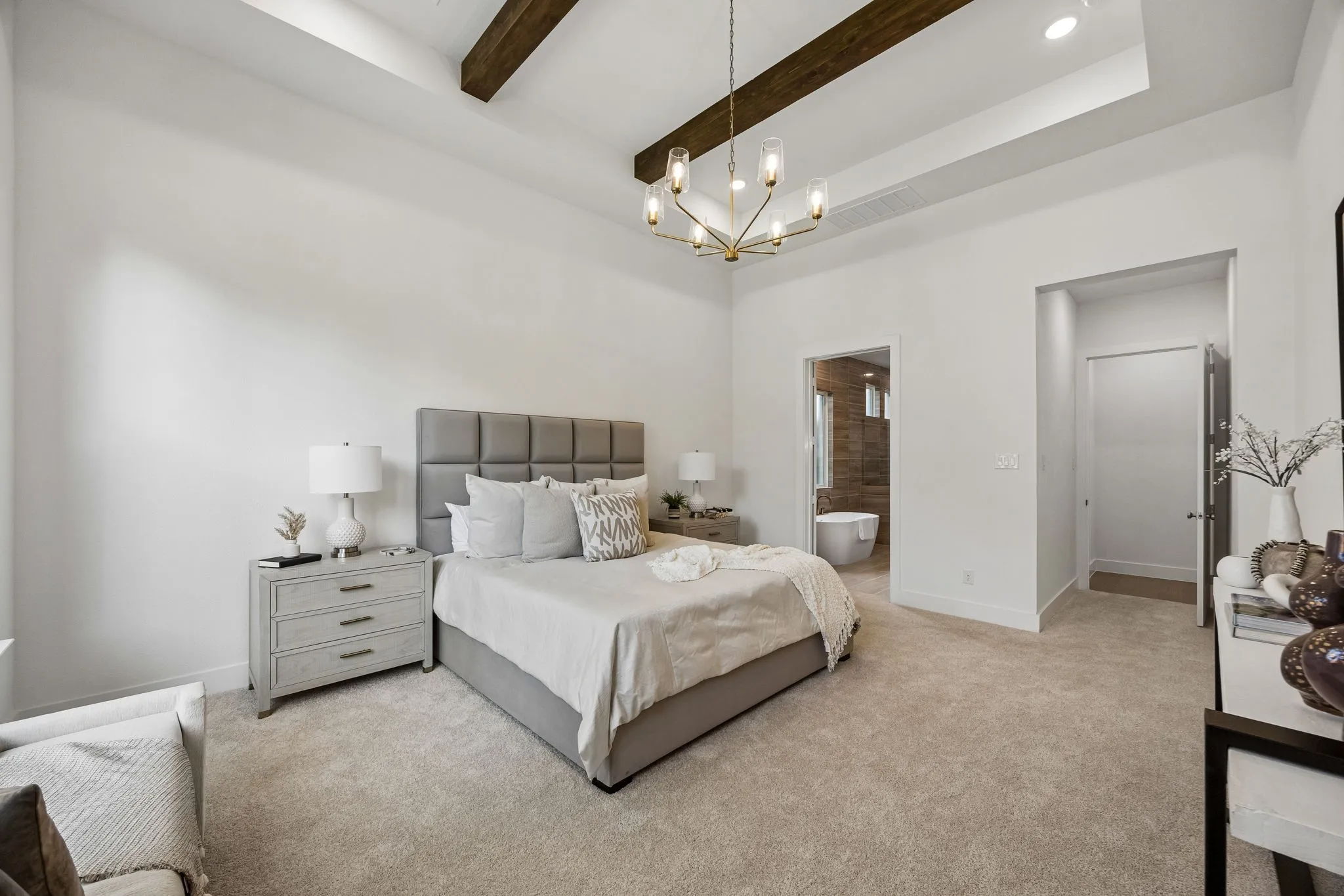 Tray ceiling with exposed wood beams, recessed lighting, and a modern chandelier
